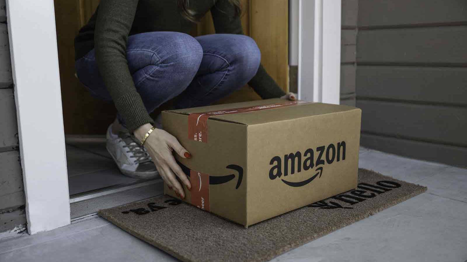 An Amazon box being brought inside from a porch