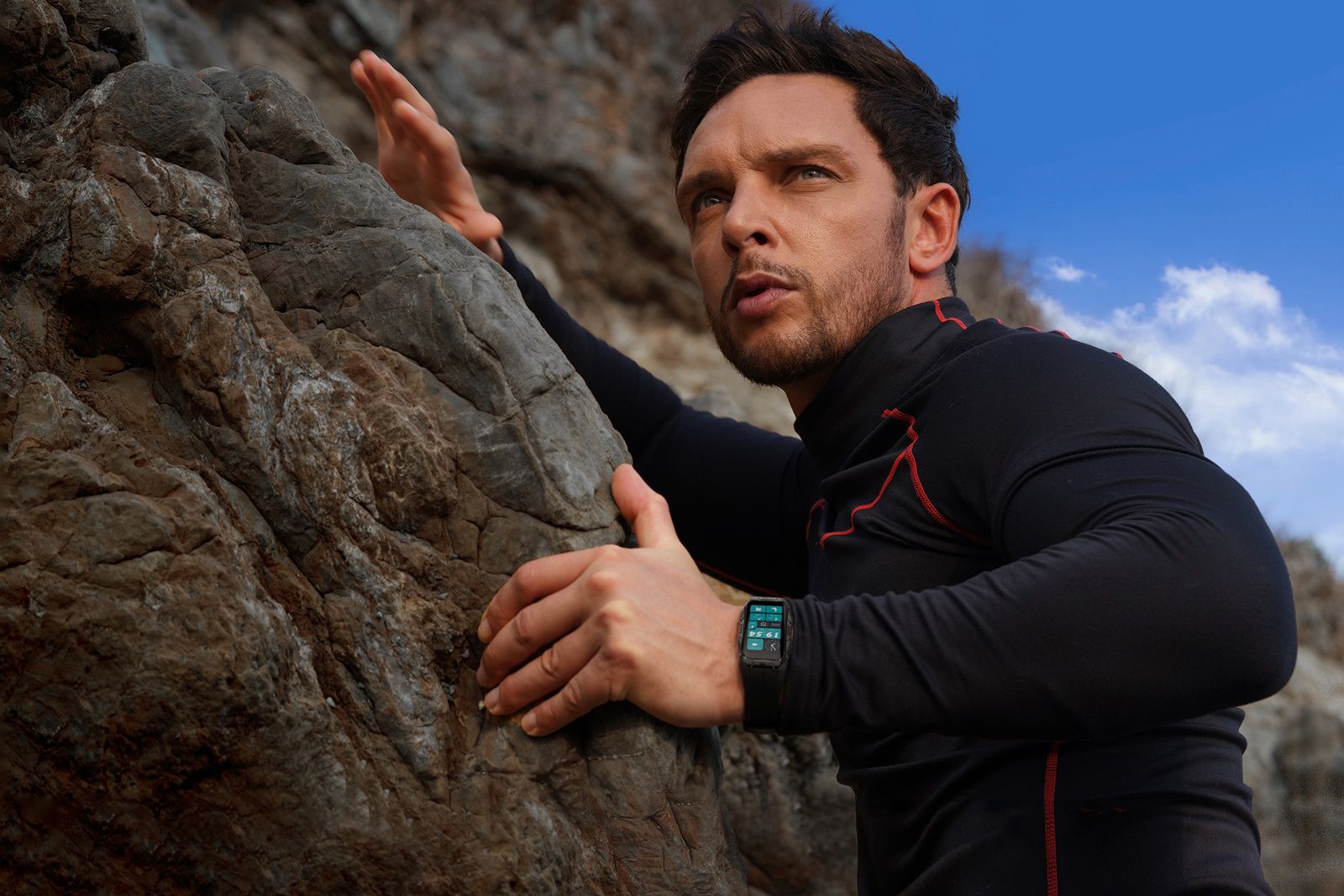 A man rock climbs while wearing the Kospet Tank X1 smartwatch. 