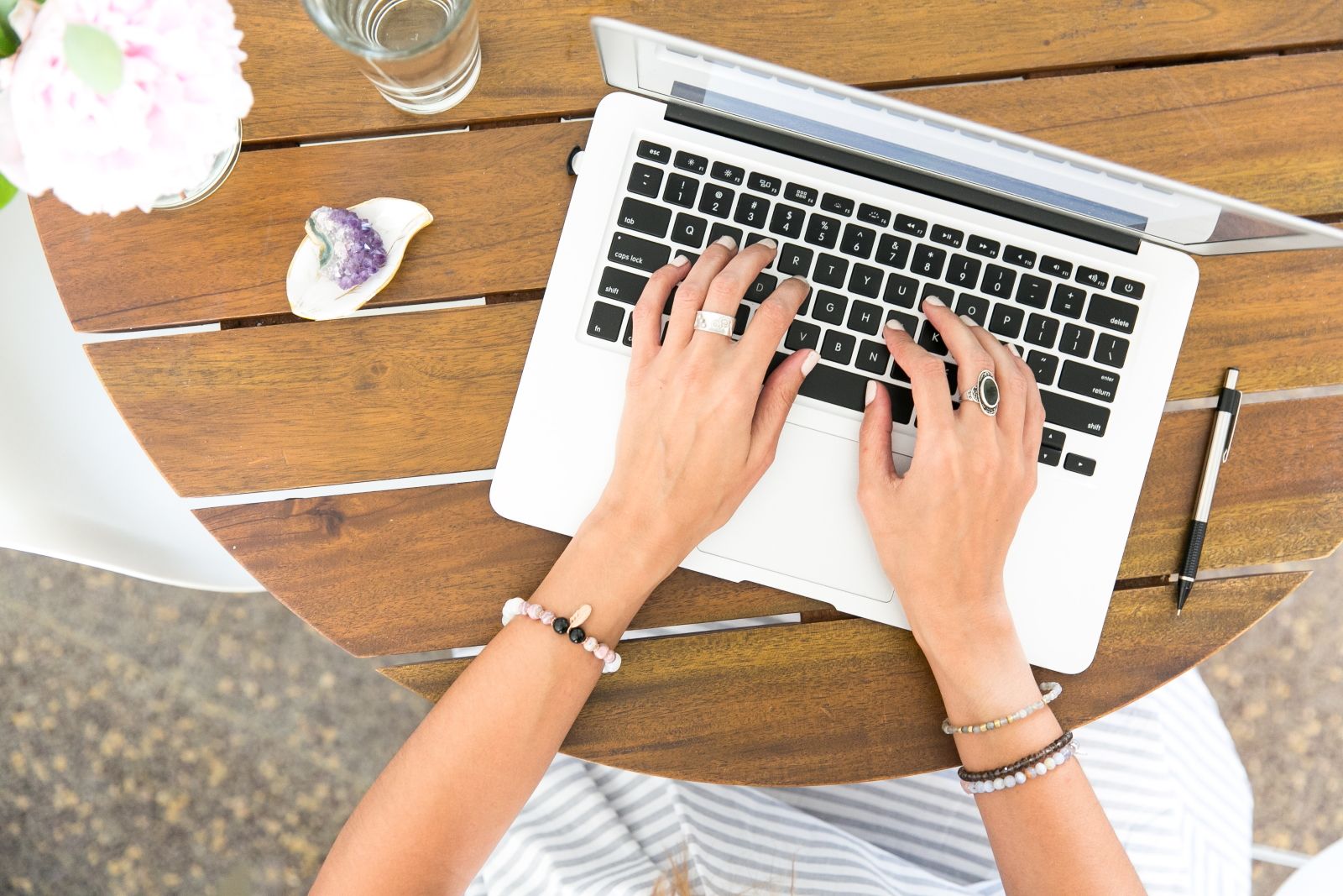 Woman Writing on Laptop at Outdoor Table