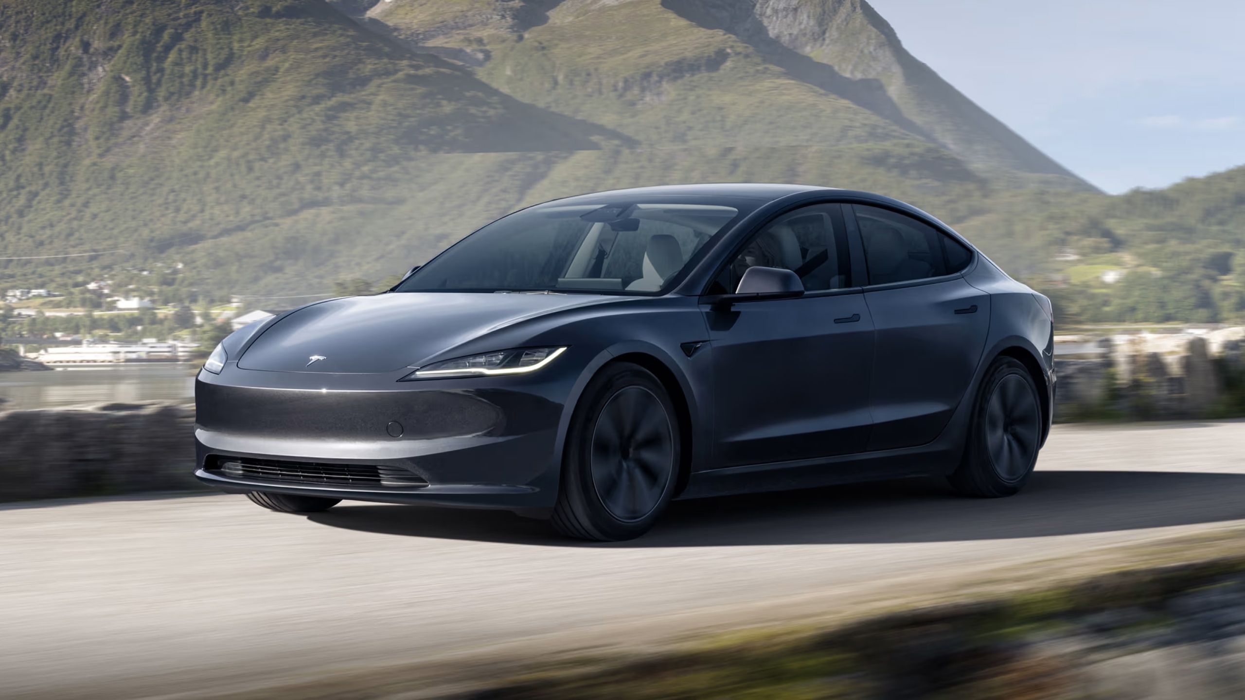 2024 Tesla Model 3 zipping past on a mountainous road