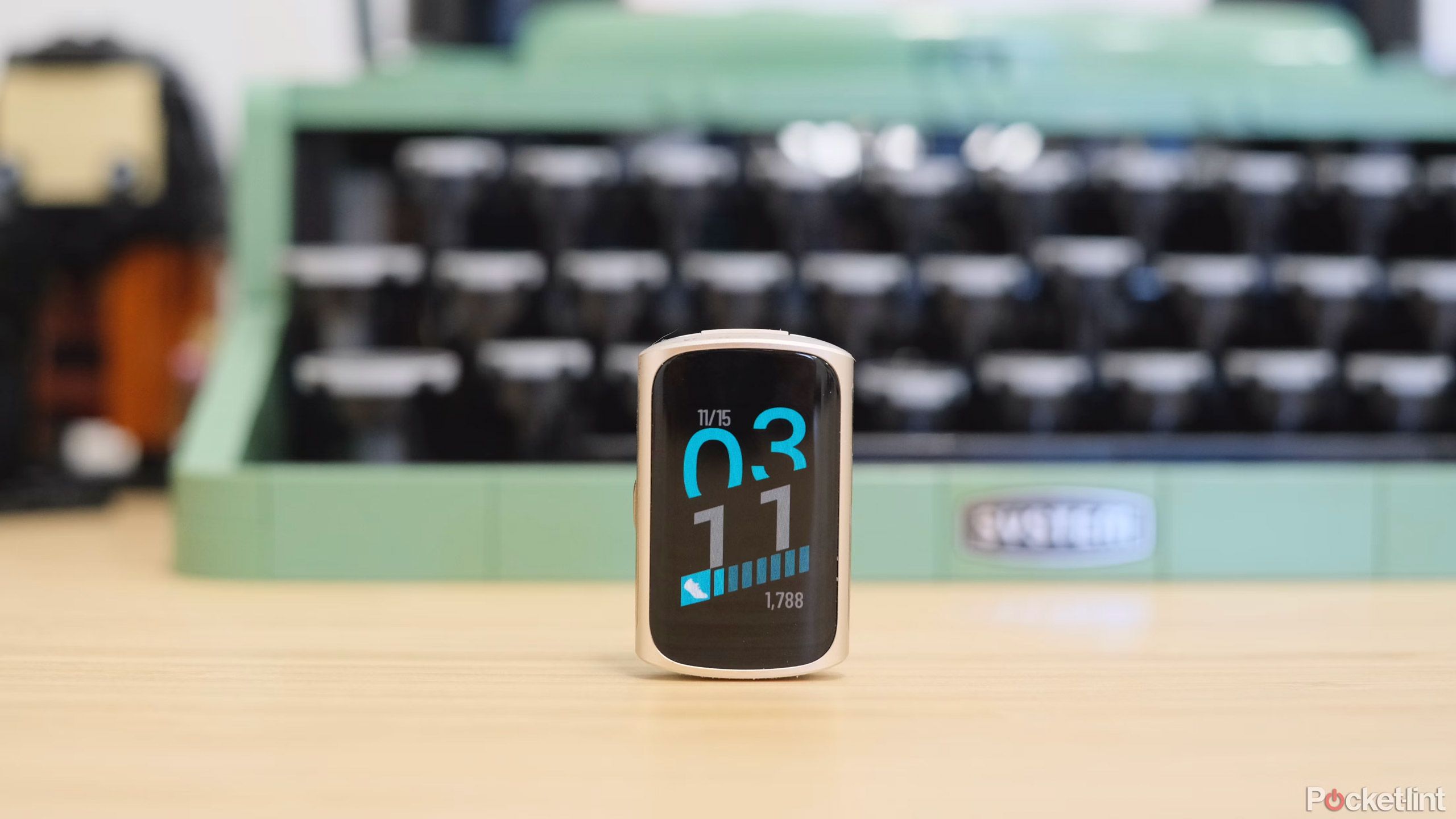 一台 Fitbit Charge 6 放在一台绿色打字机前