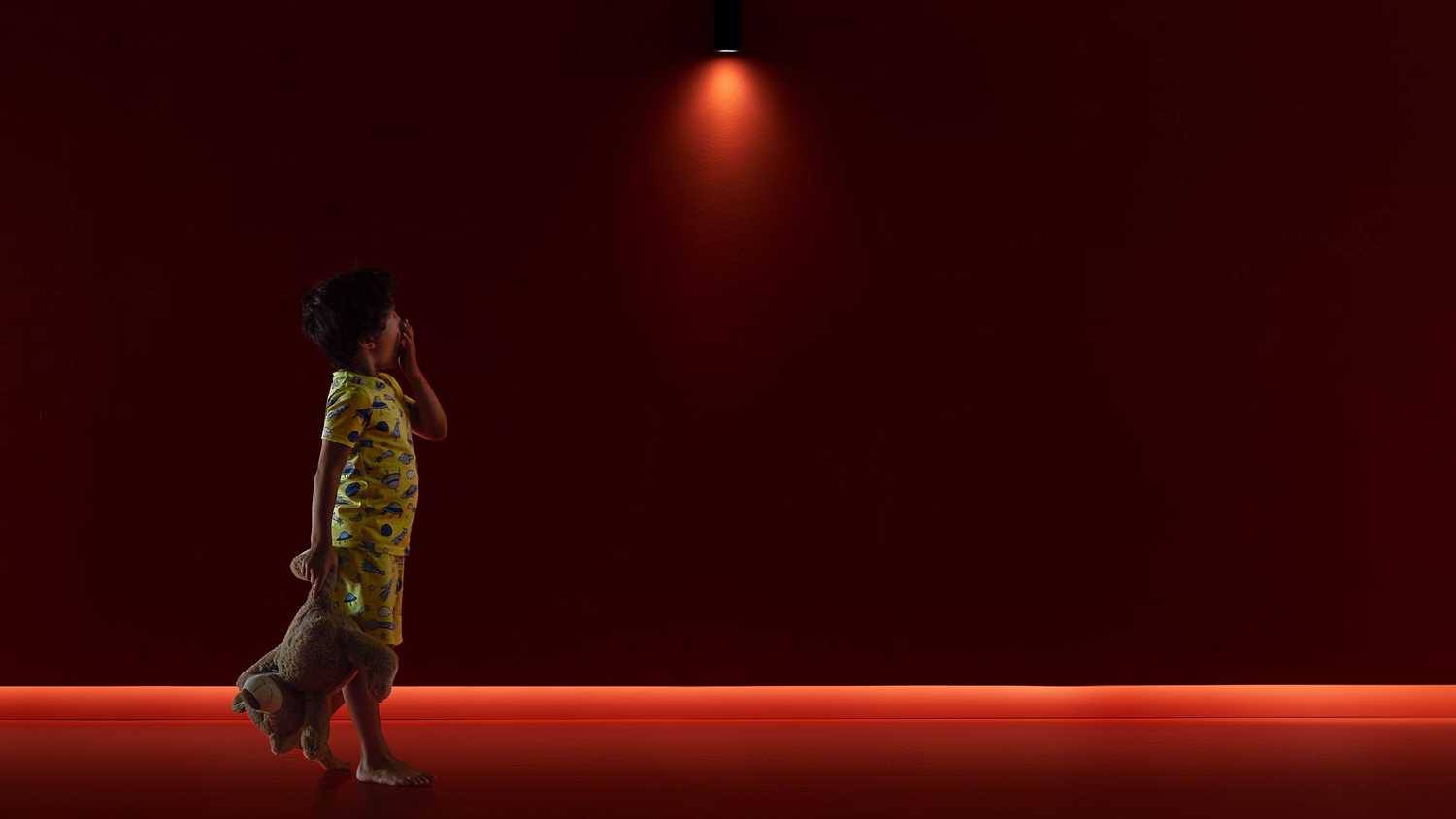 A Wiz smart light bulb casts an orange light on a toddler