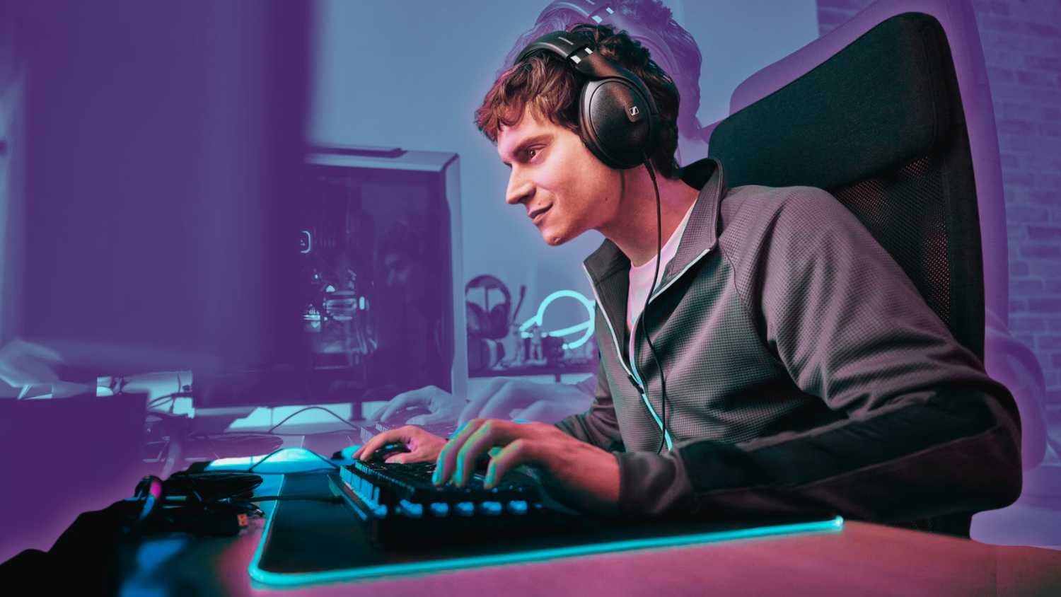 A person sitting at a desk gaming on a PC while wearing the Sennheiser HD 620S headphones.  