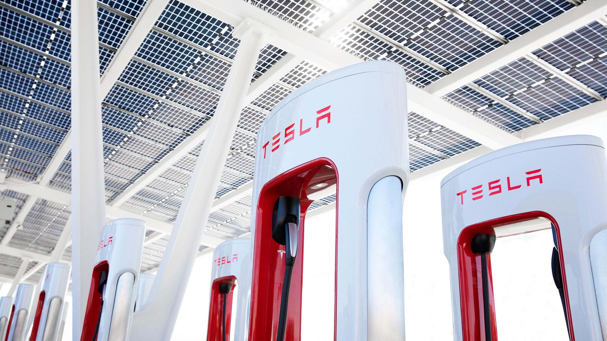 A row of Tesla Superchargers under a solar roof