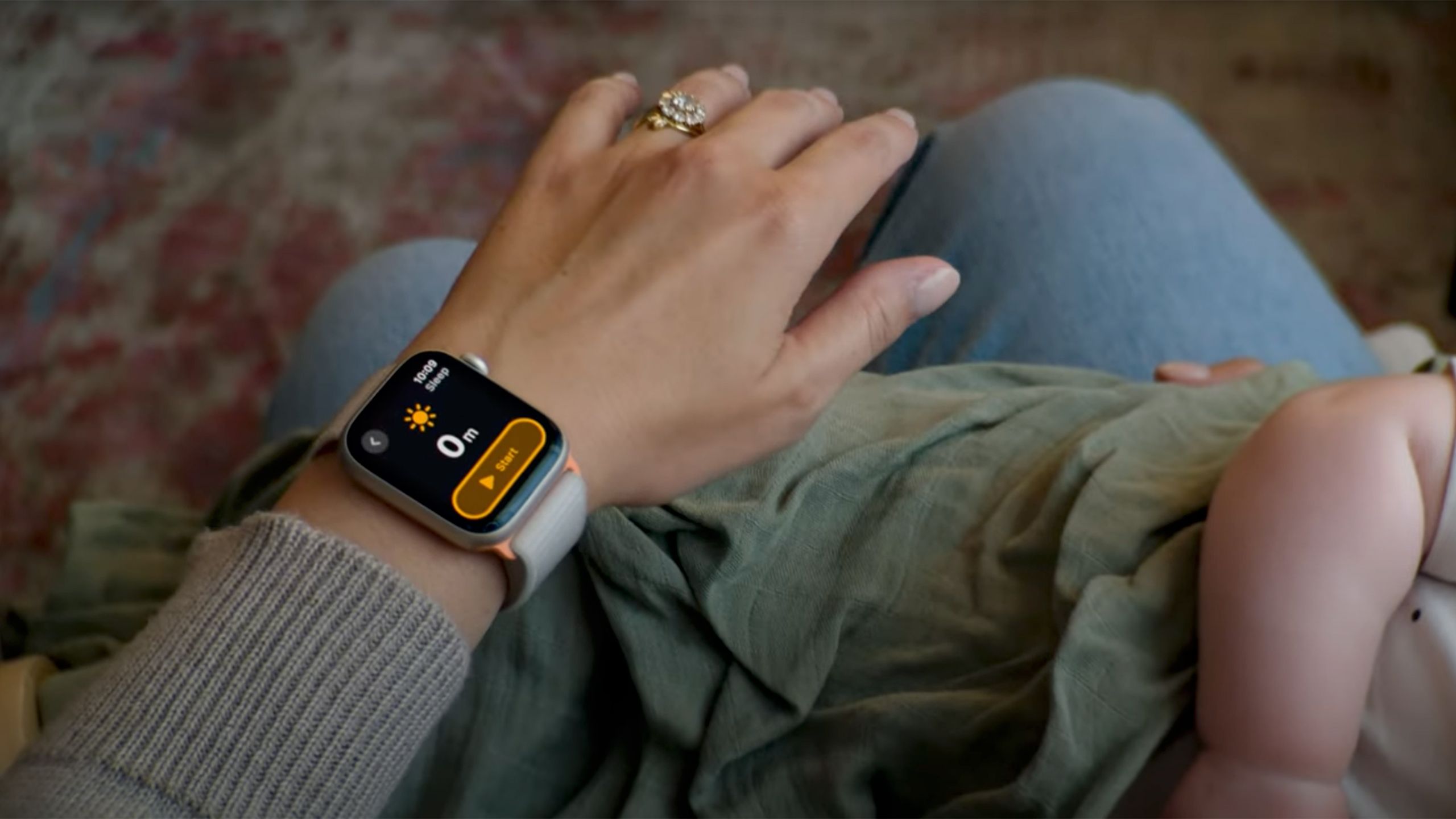 An Apple Watch on a wrist with a timer displayed while they hold a baby. 