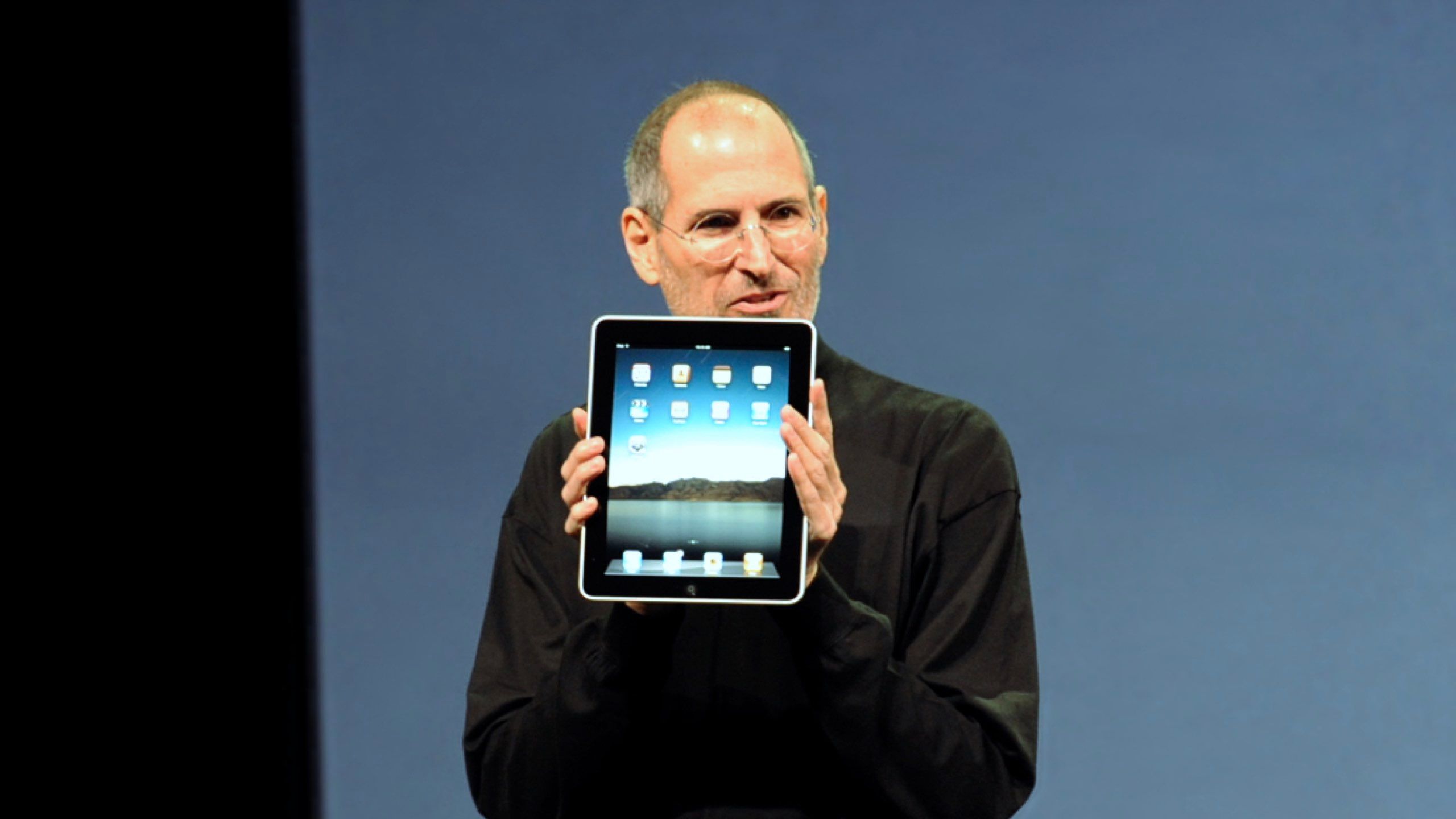 Steve Jobs holding an original iPad.