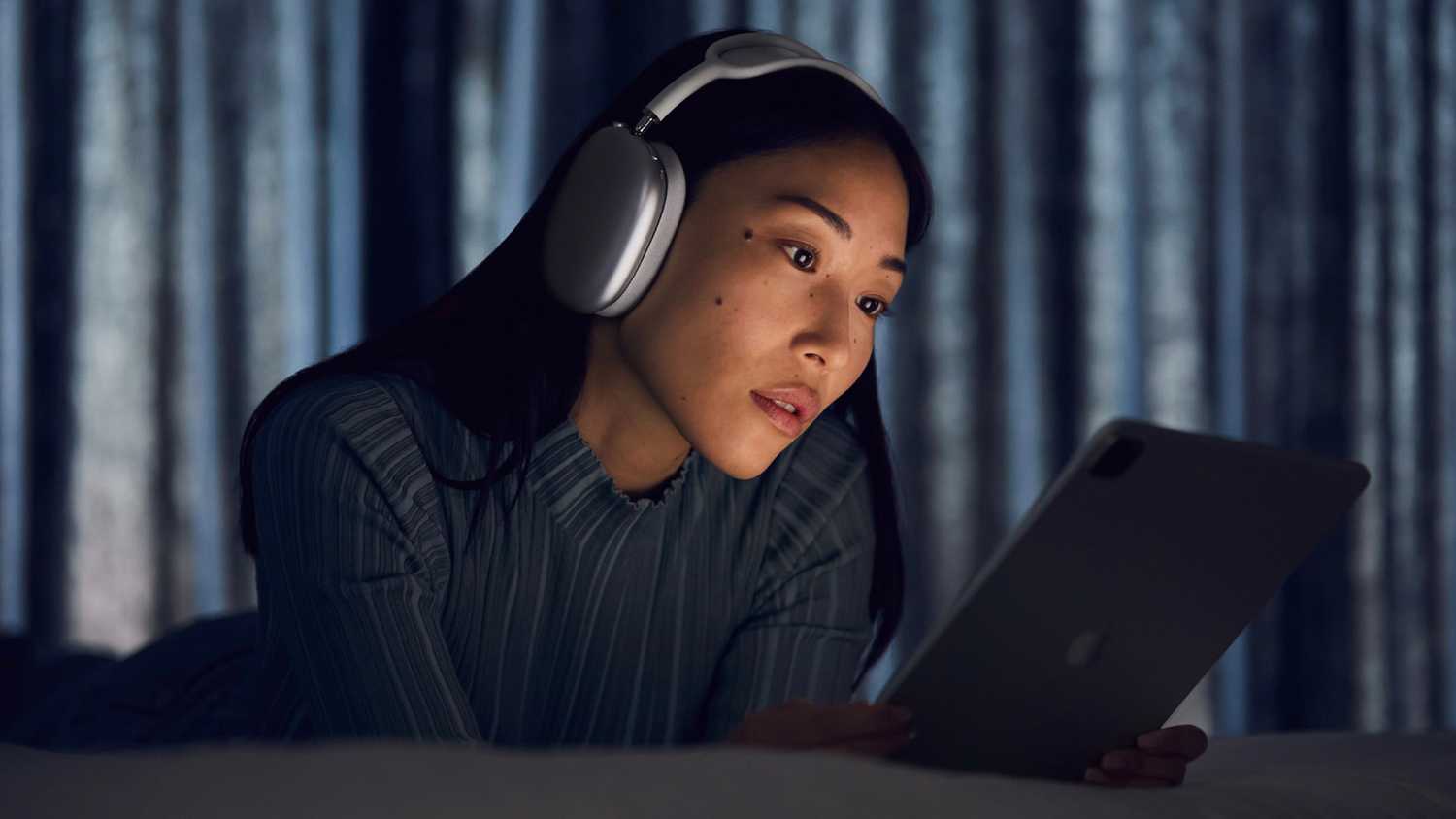 A woman wearing AirPods Max while on an iPad.