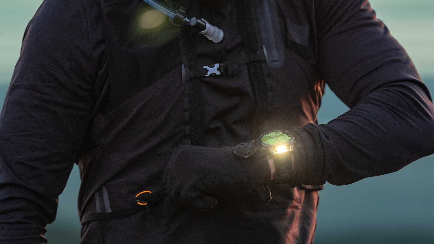 A person stands with their wrist held up while wearing the Garmin fenix 8 with the flashlight on.