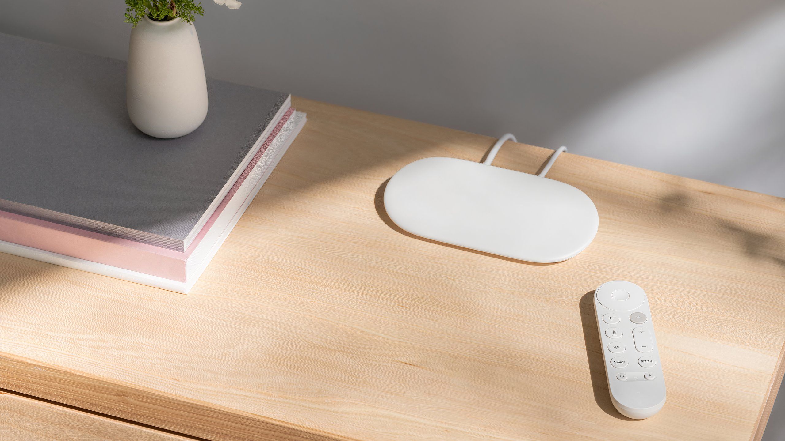 A Google TV Streamer and remote on a desktop.