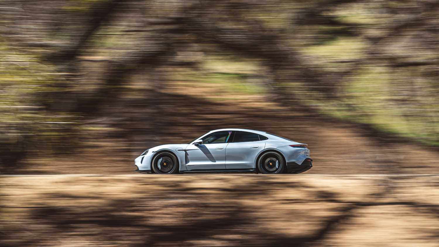 A side profile of the 2024 Porsche Taycan on the road.