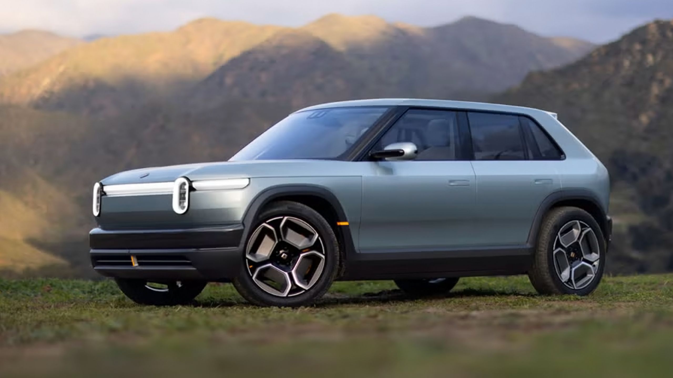 A pre-production Rivian R3 parked in the mountains.