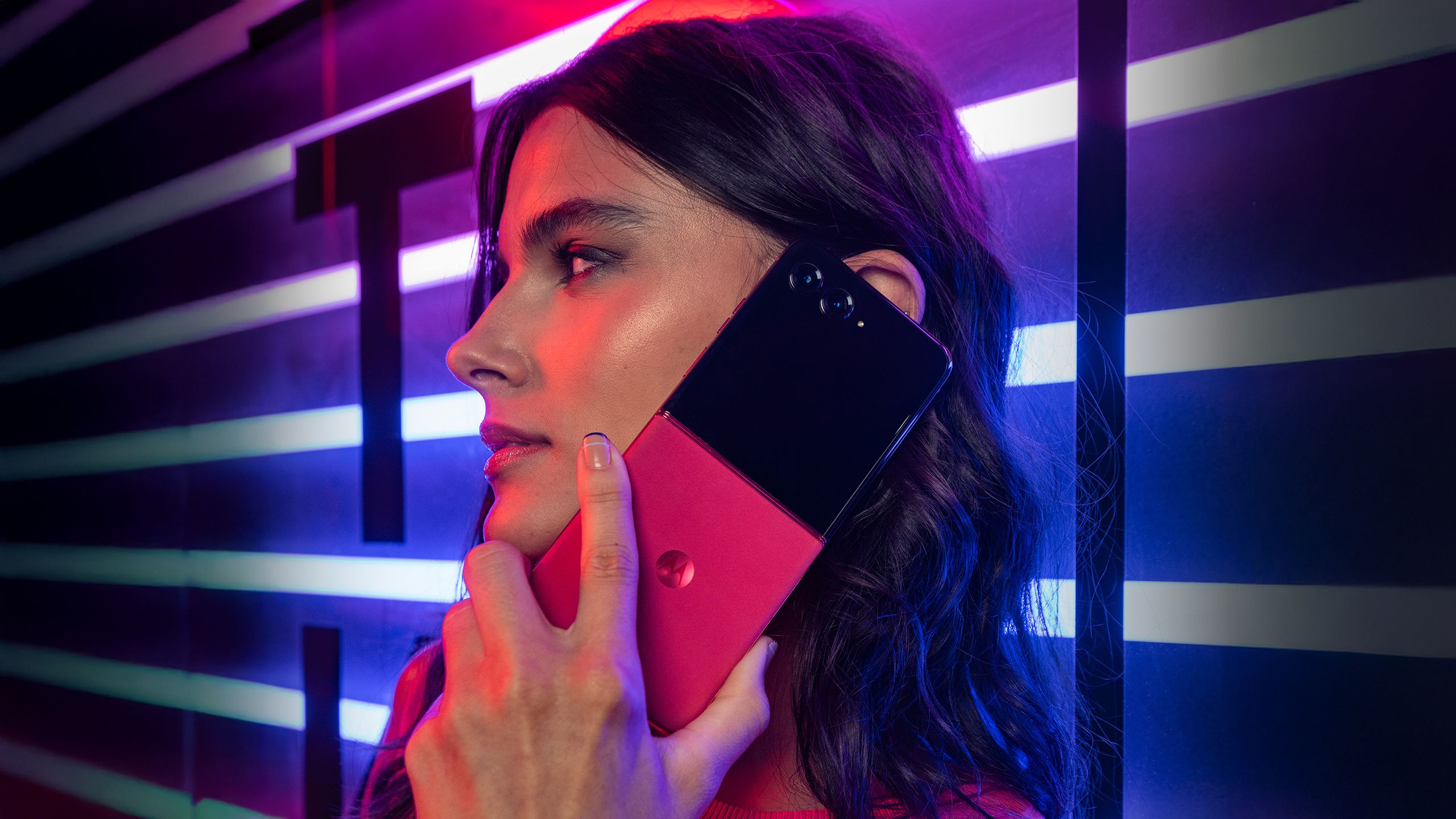 Motorola Razr+ in hand in dark red lighting. 