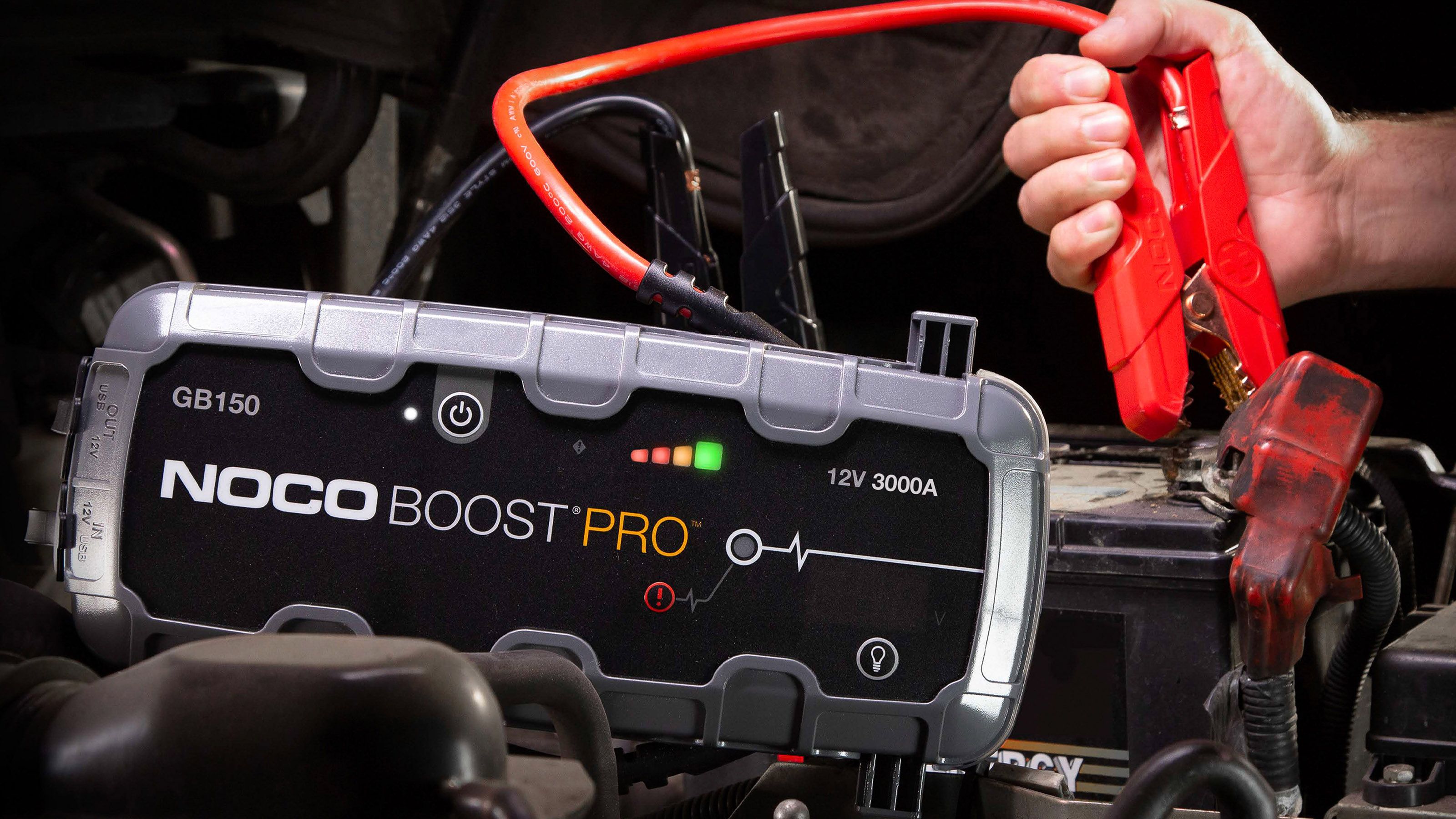 A NOCO Boost Pro GB 150 jump pack being hooked to the battery of a car. 
