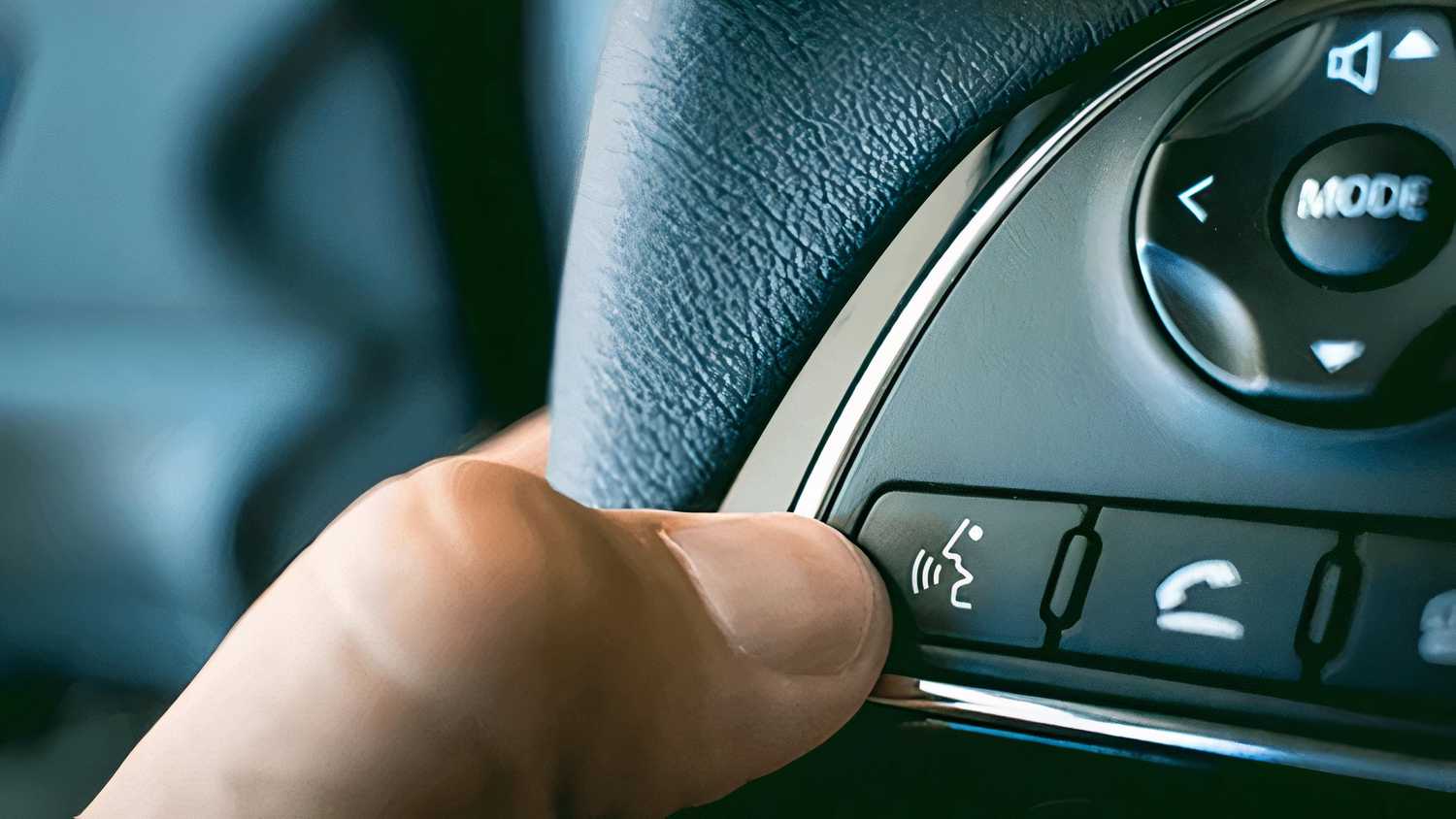 Foto tangan yang mengaktifkan tombol asisten suara di dalam mobil.