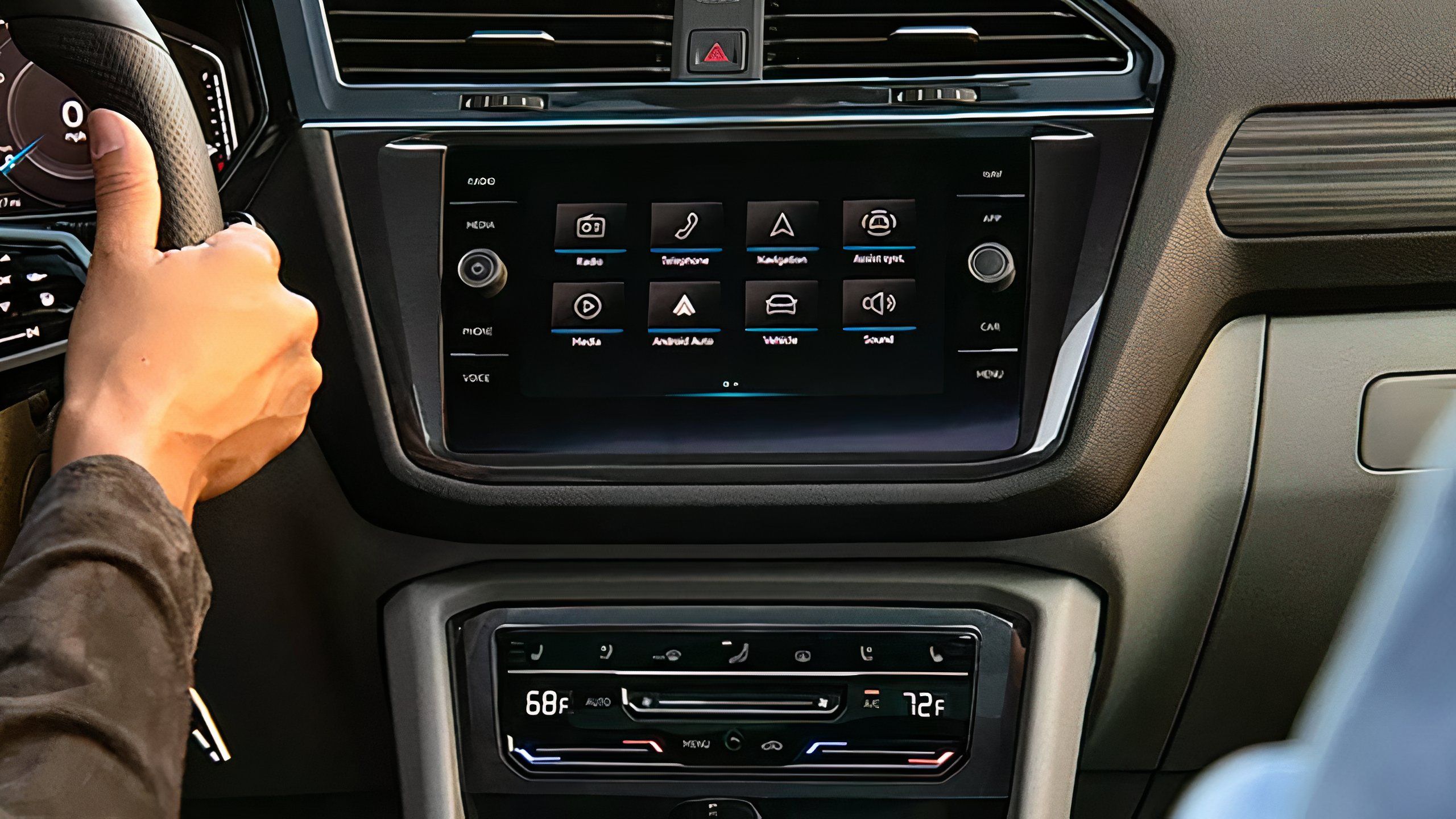 A driver operates their Volkswagen car while using the on-board infotainment system. 