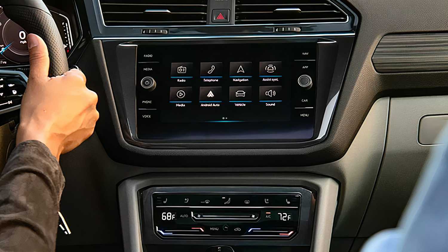 A driver operates their Volkswagen car while using the on-board infotainment system. 