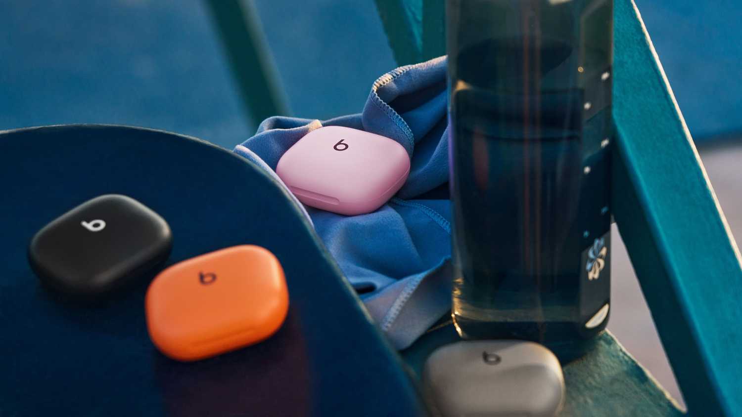 Powerbeats Fit in their cases on a table. 