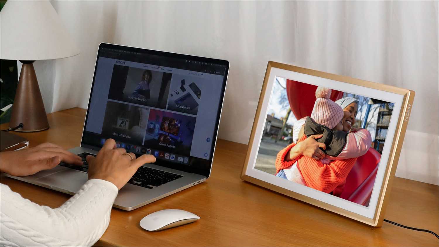 Las manos escriben en una computadora portátil al lado de un marco de fotos digital