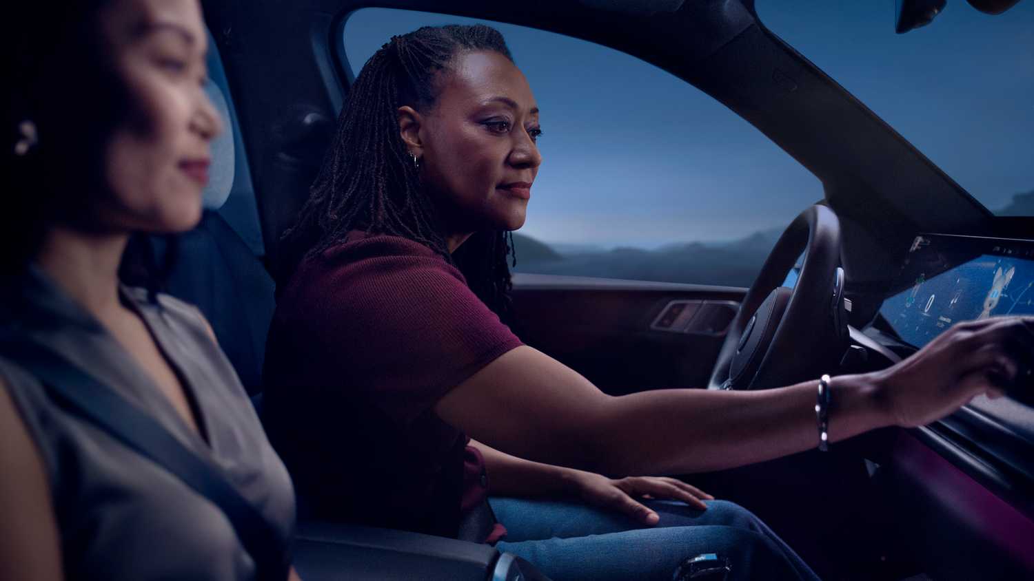 A still photo of a woman reaching out to adjust settings on her infotainment screen.