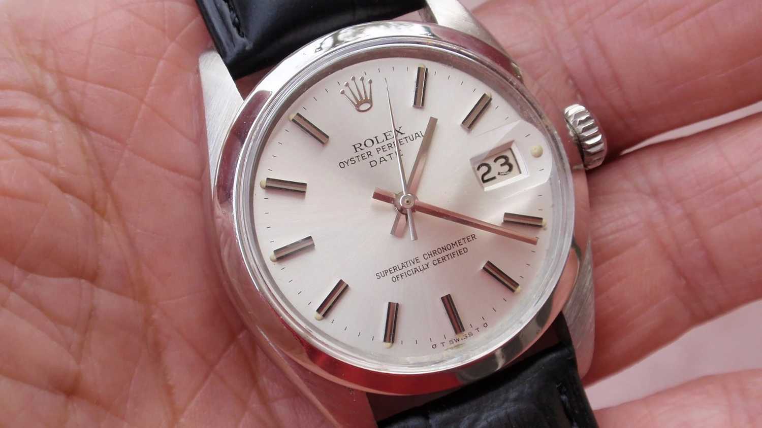 A still photo of a Rolex wristwatch being held in someone's hand. 