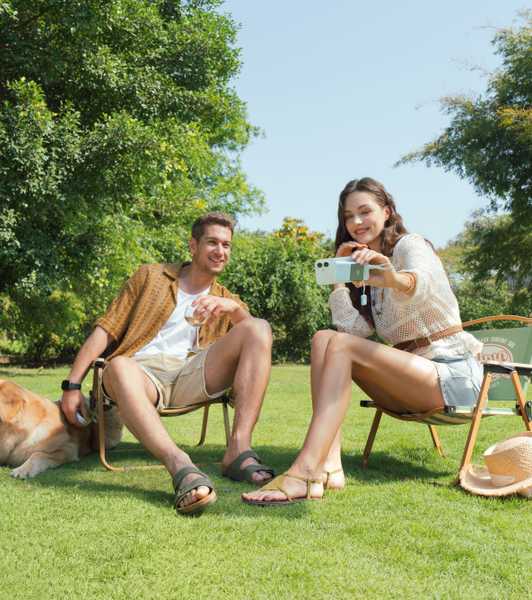 Couple sitting on chairs, woman holding a phone with the INIU Pocket Rocket P50 attached