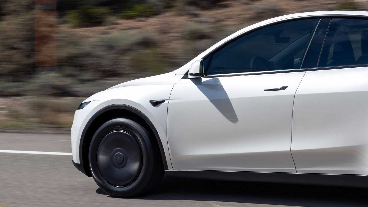 A still photo of a Tesla Model Y on the road. 