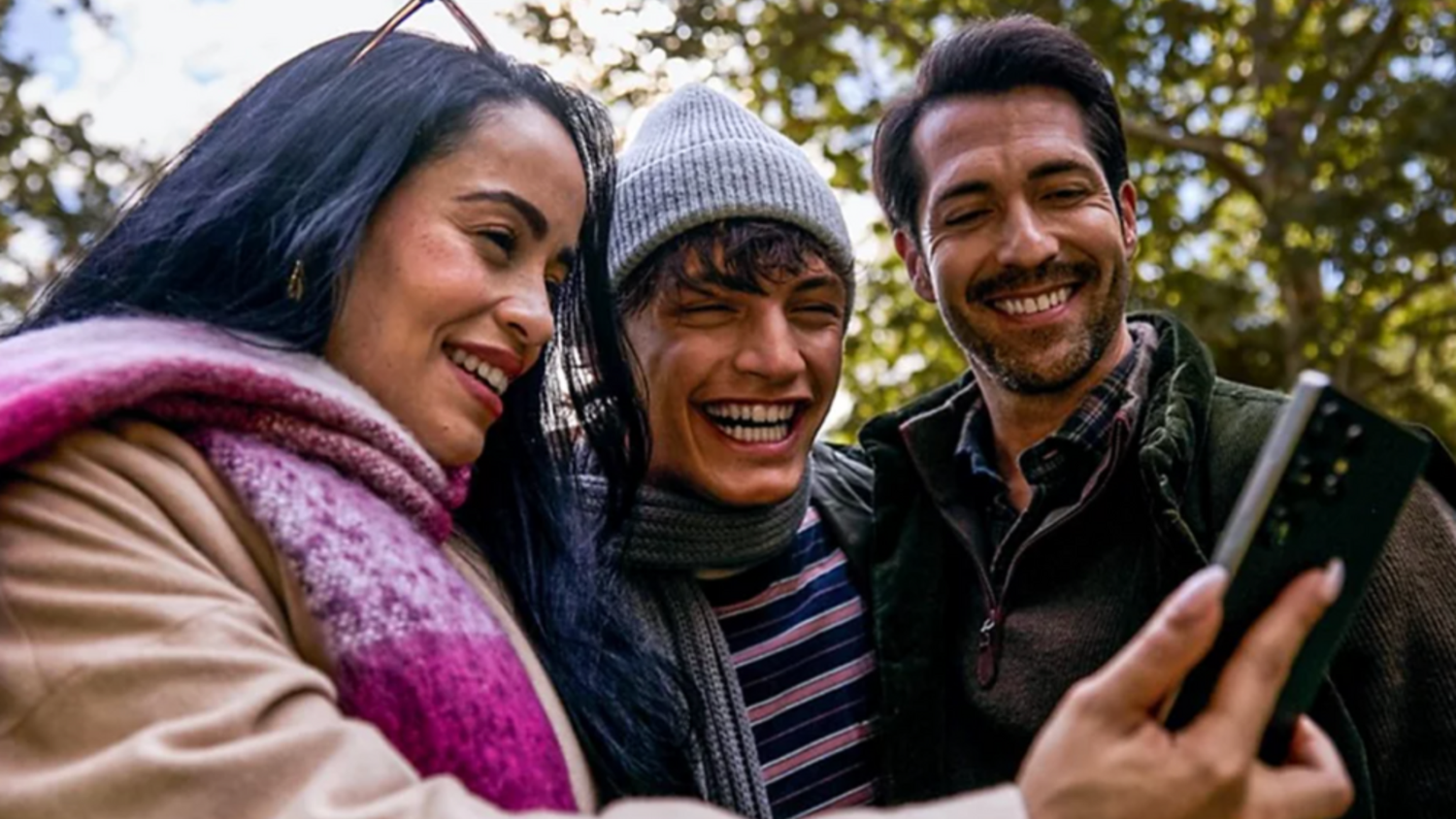 Three people looking at a phone and smiling