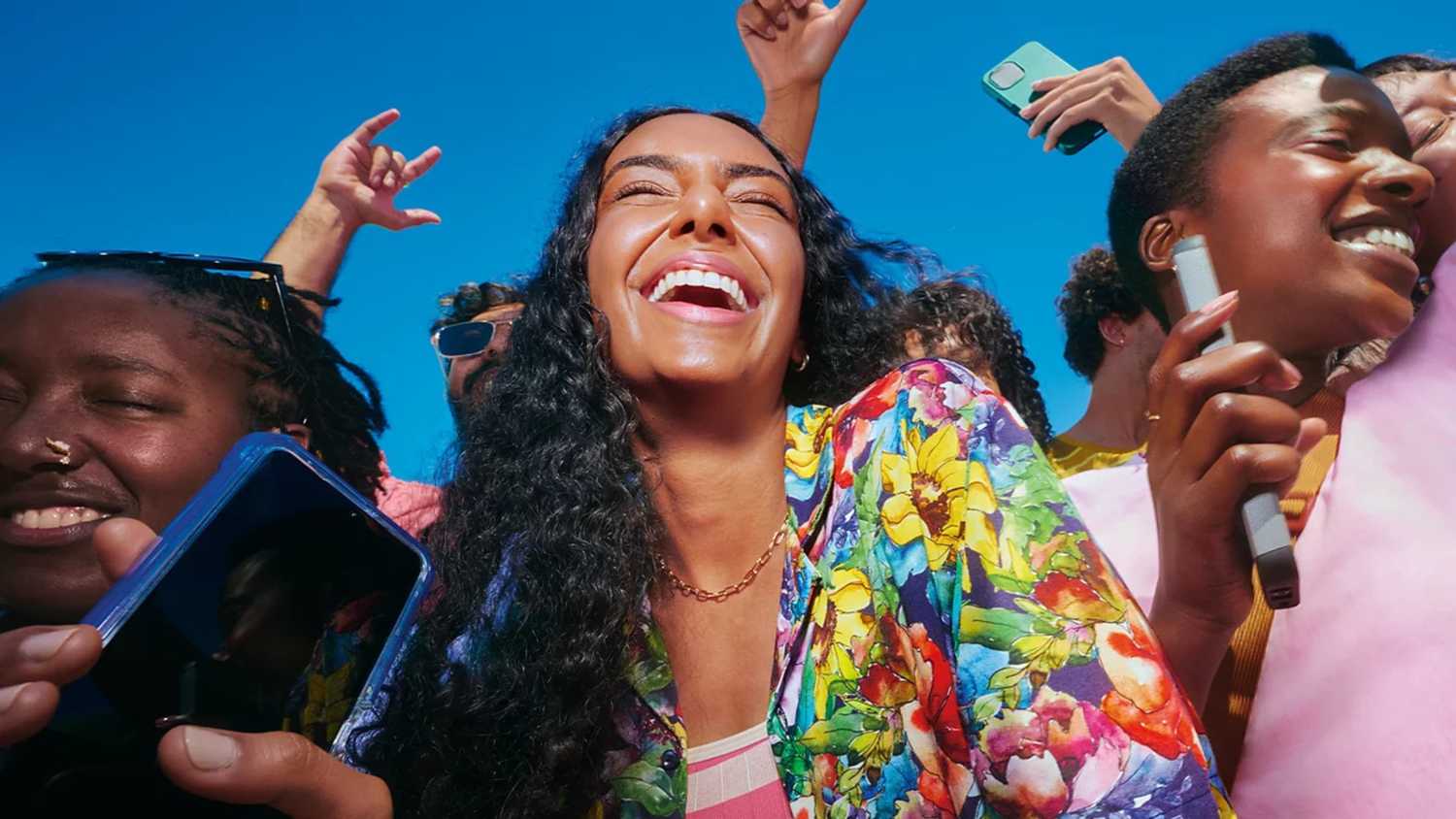 Friends laughing outdoors, holding smartphones