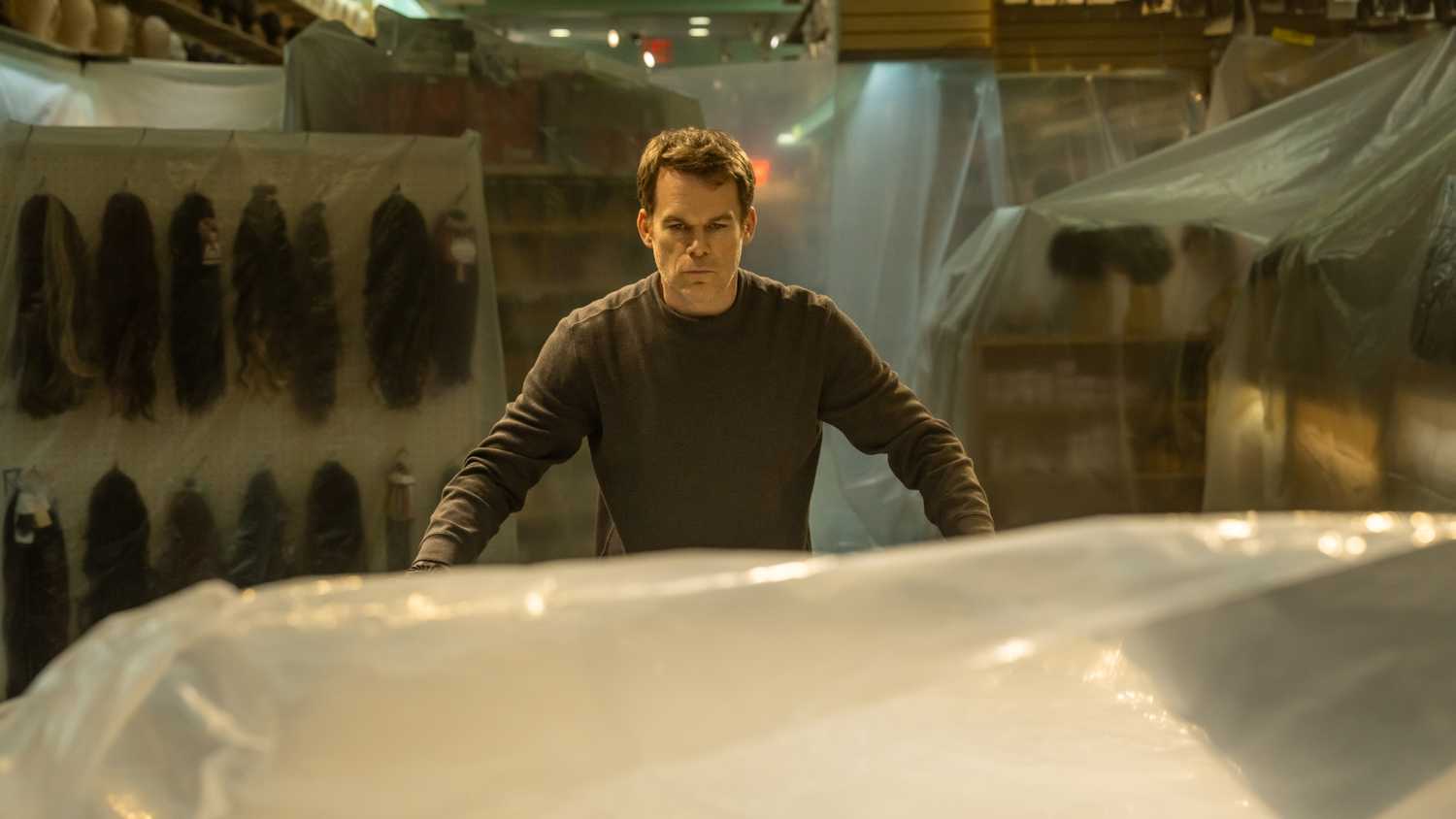 Michael C. Hall as Dexter Morgan covering a kill room in plastic, staring at his kill table in Dexter: Resurrection season 1.