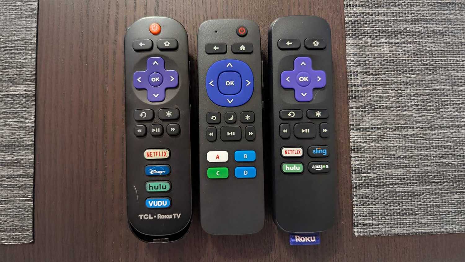 A still photo of an Insignia Roku remote next to stock Roku remotes.