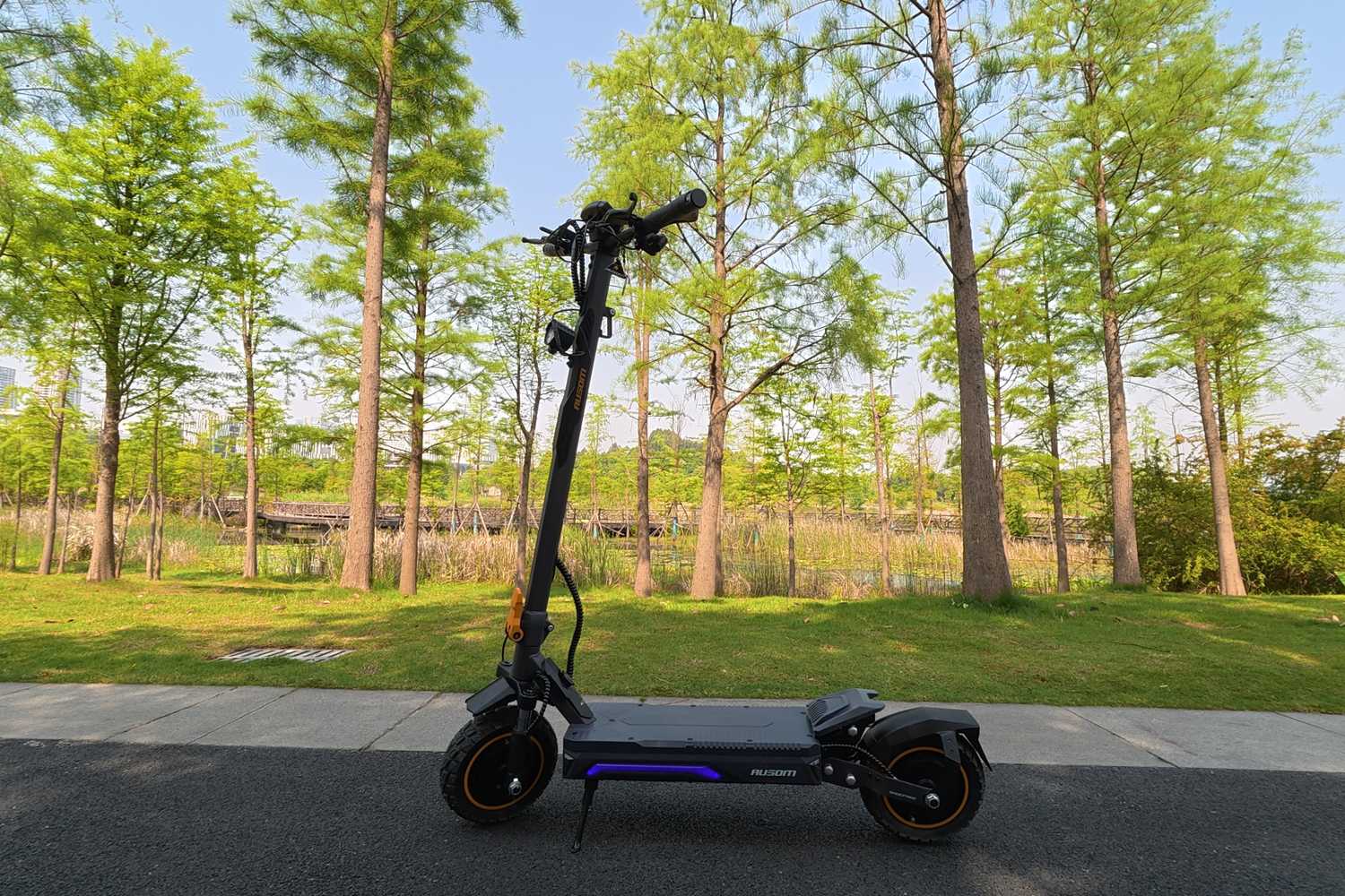 The Ausom K20 Pro Dual Motor on the street with trees in the background.