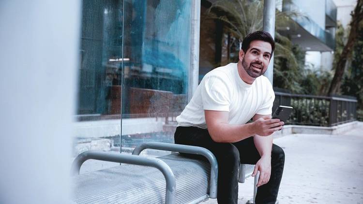 Man sitting on a metal bench using his phone.