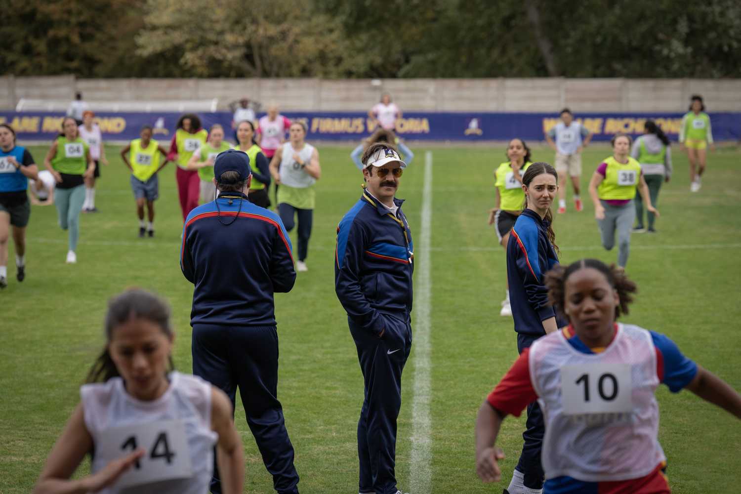 Ted Lasso smiling at a Lady Greyhounds game in Richmond in Ted Lasso season 4.