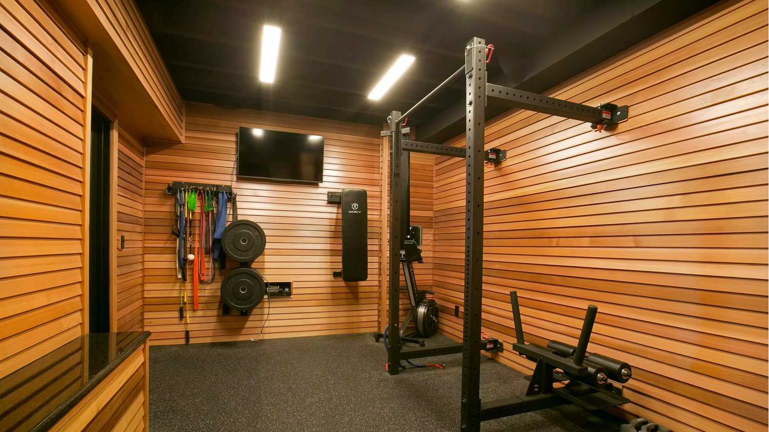 A home gym with a power rack and a wall-mounted TV.