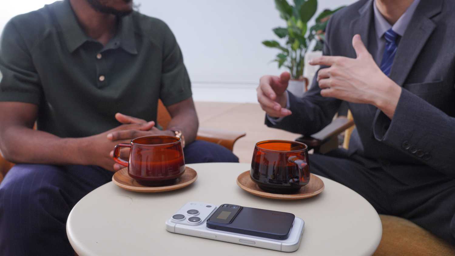 Two men having a conversation coffee with the Comu Action Pro on a table attached to a phone.