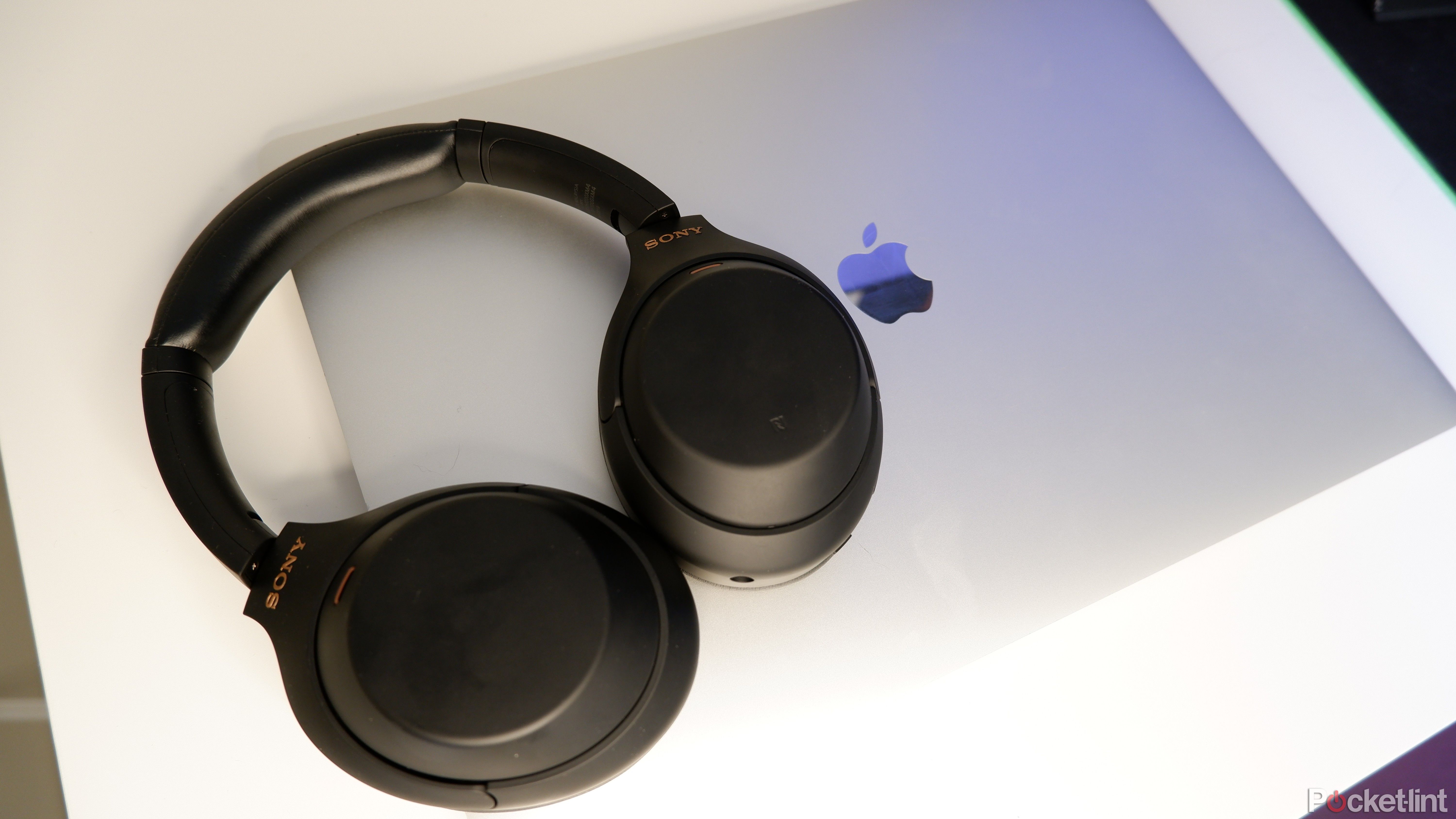 A pair of Sony WH-1000XM4s connected to a closed Macbook Pro.