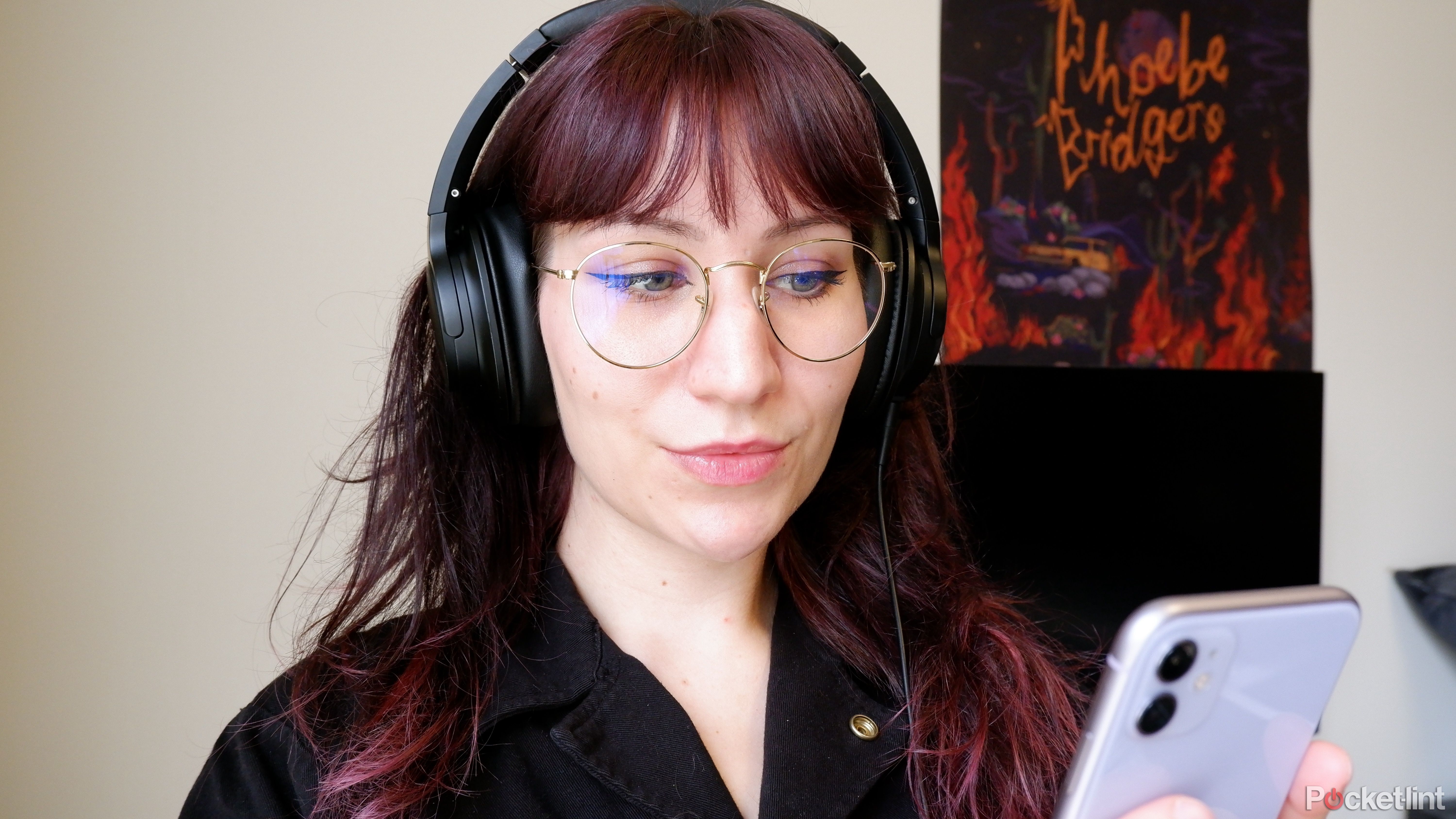 A woman listening to music on a phone using wired headphones.
