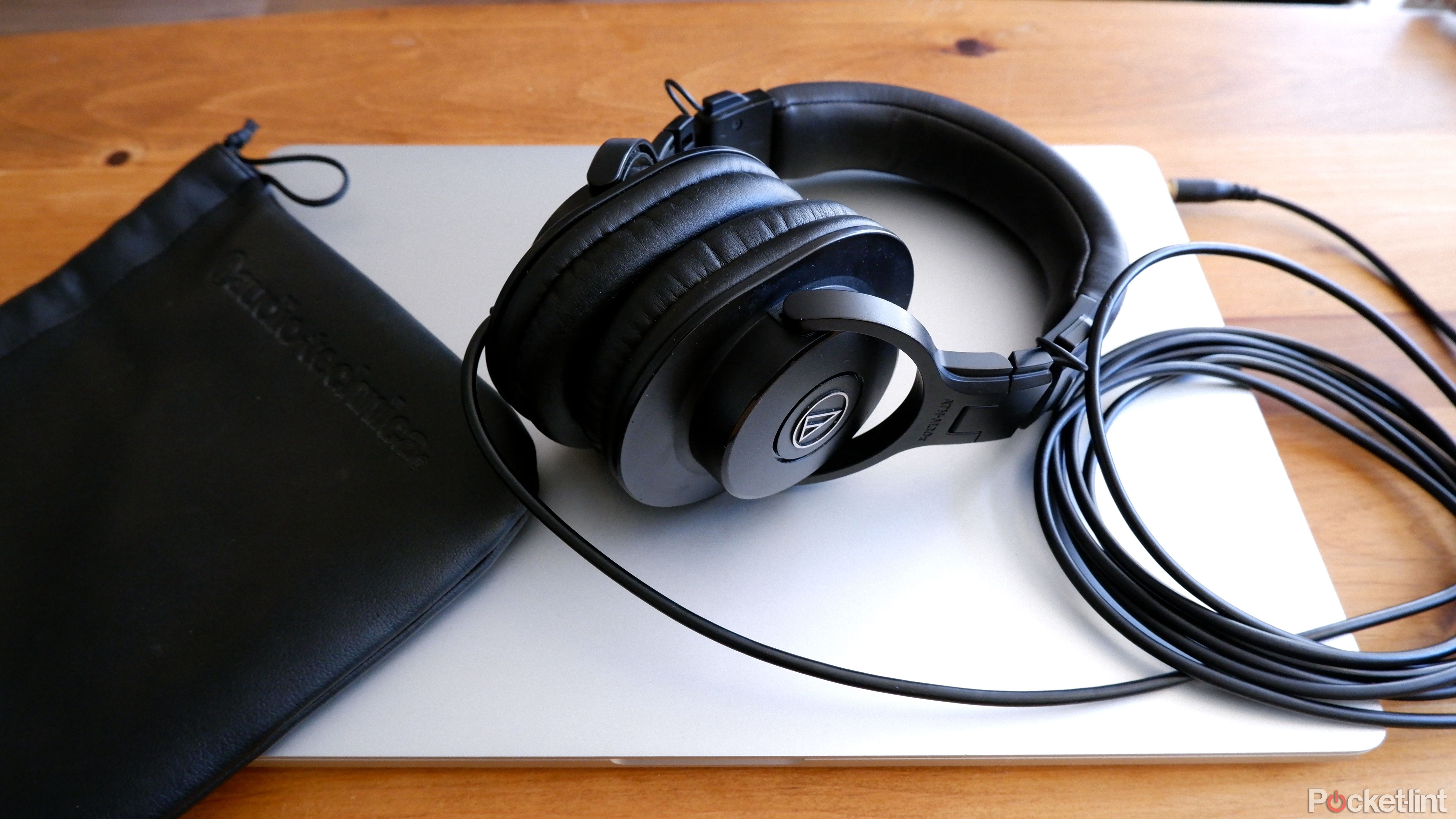 The Audio-Technica ATH-M30x plugged into a Macbook Pro, with the soft case beside it.