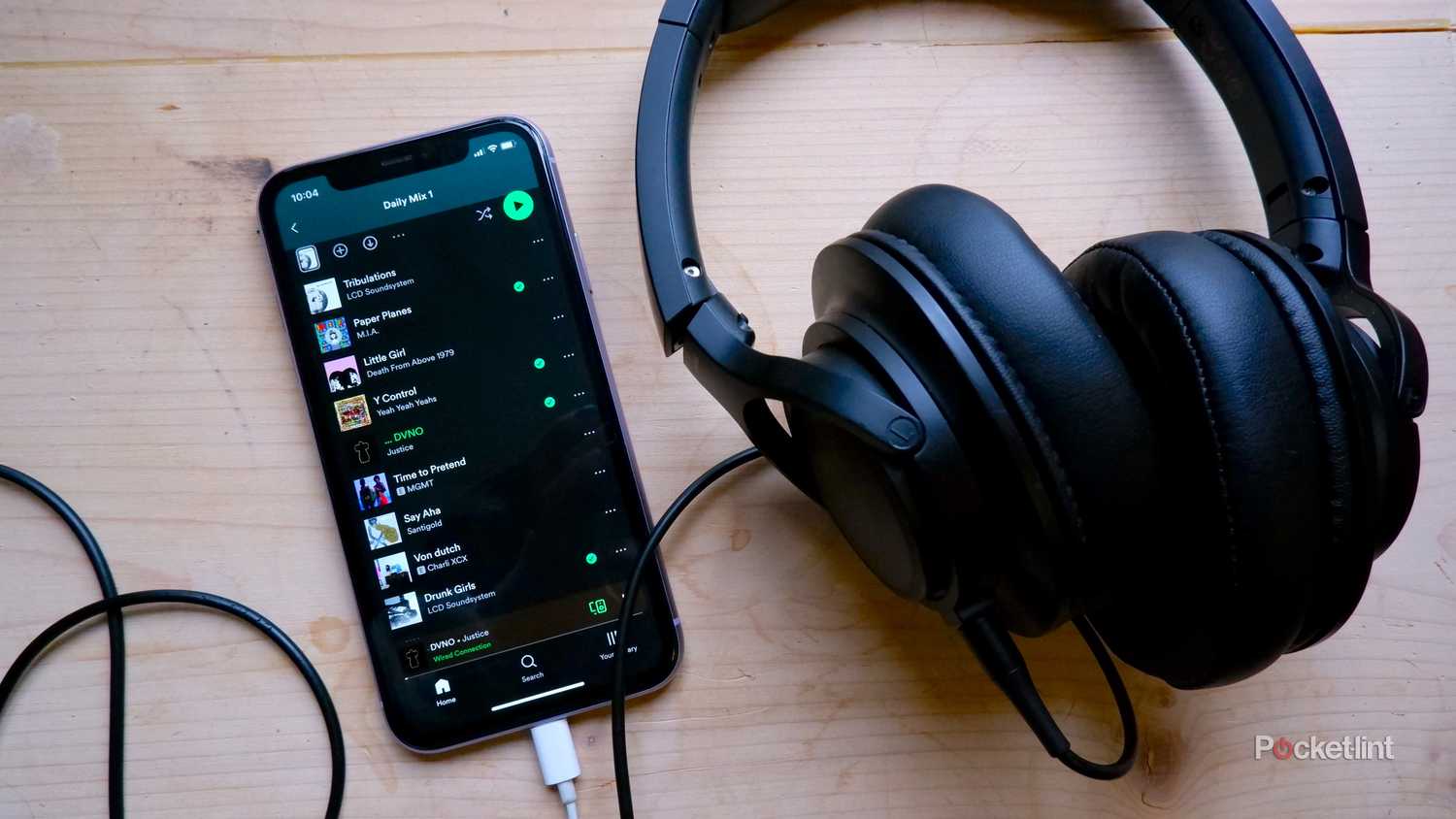 Headphones plugged into an iPhone with Spotify open.