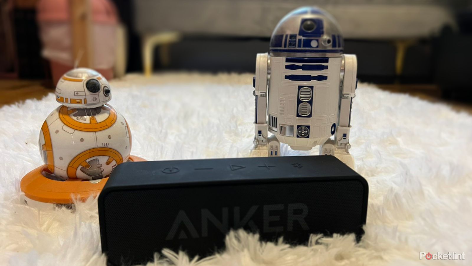 Anker Soundcore bluetooth speaker on carpet next to droids