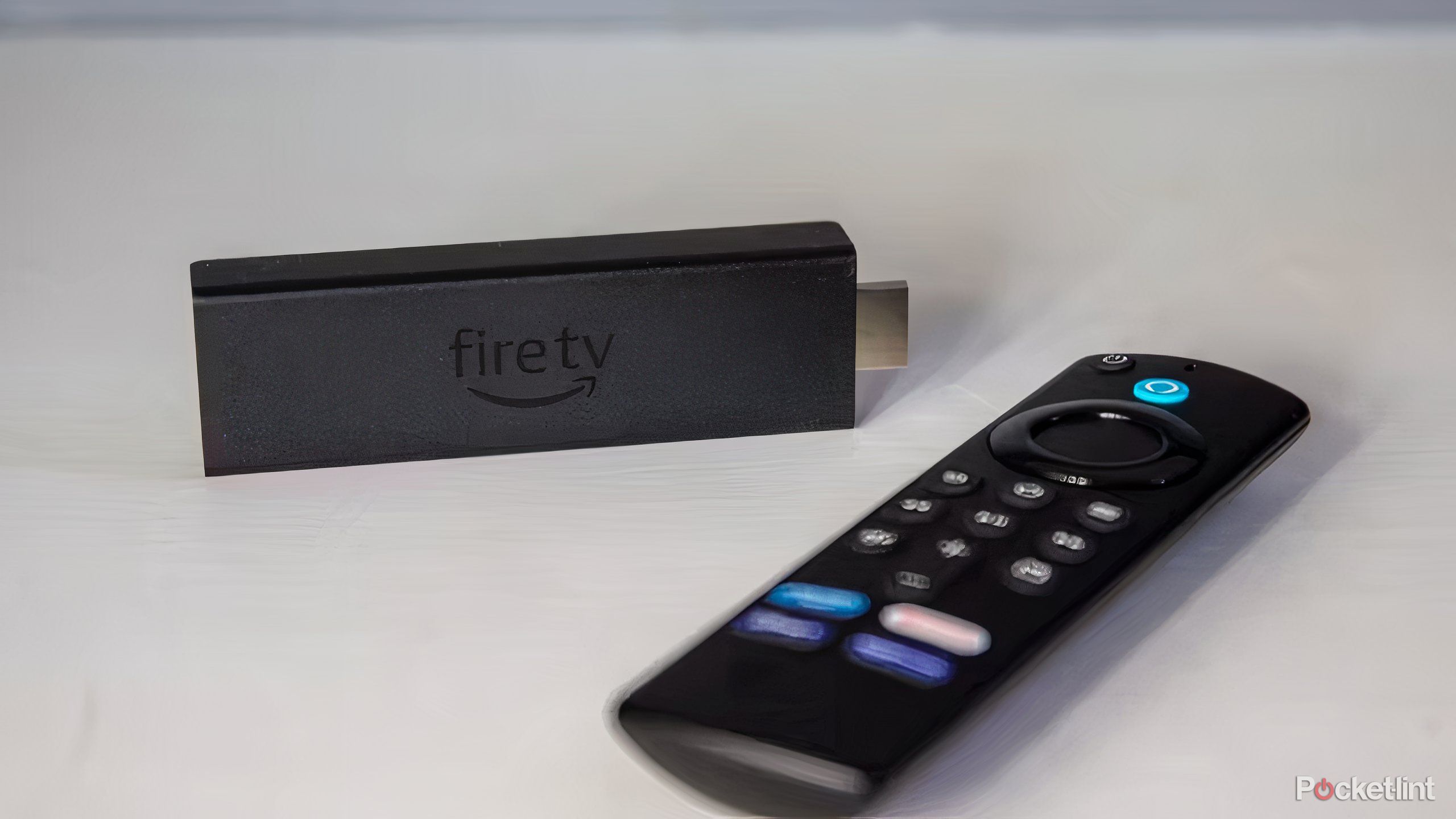 An Amazon Fire TV Stick and remote on a flat surface. 