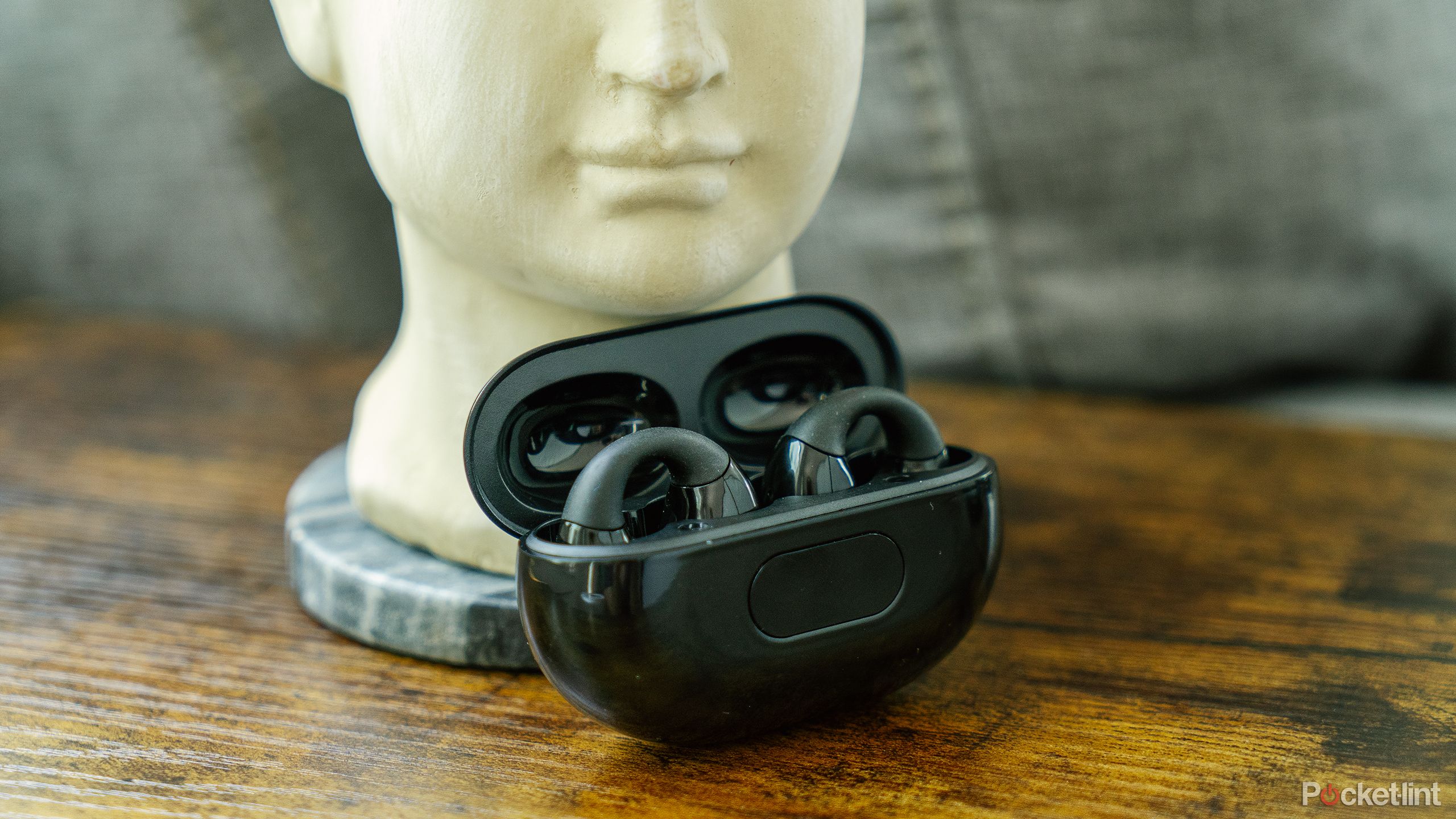 The Dufiga Open-Ear Headphones case on a wood table.