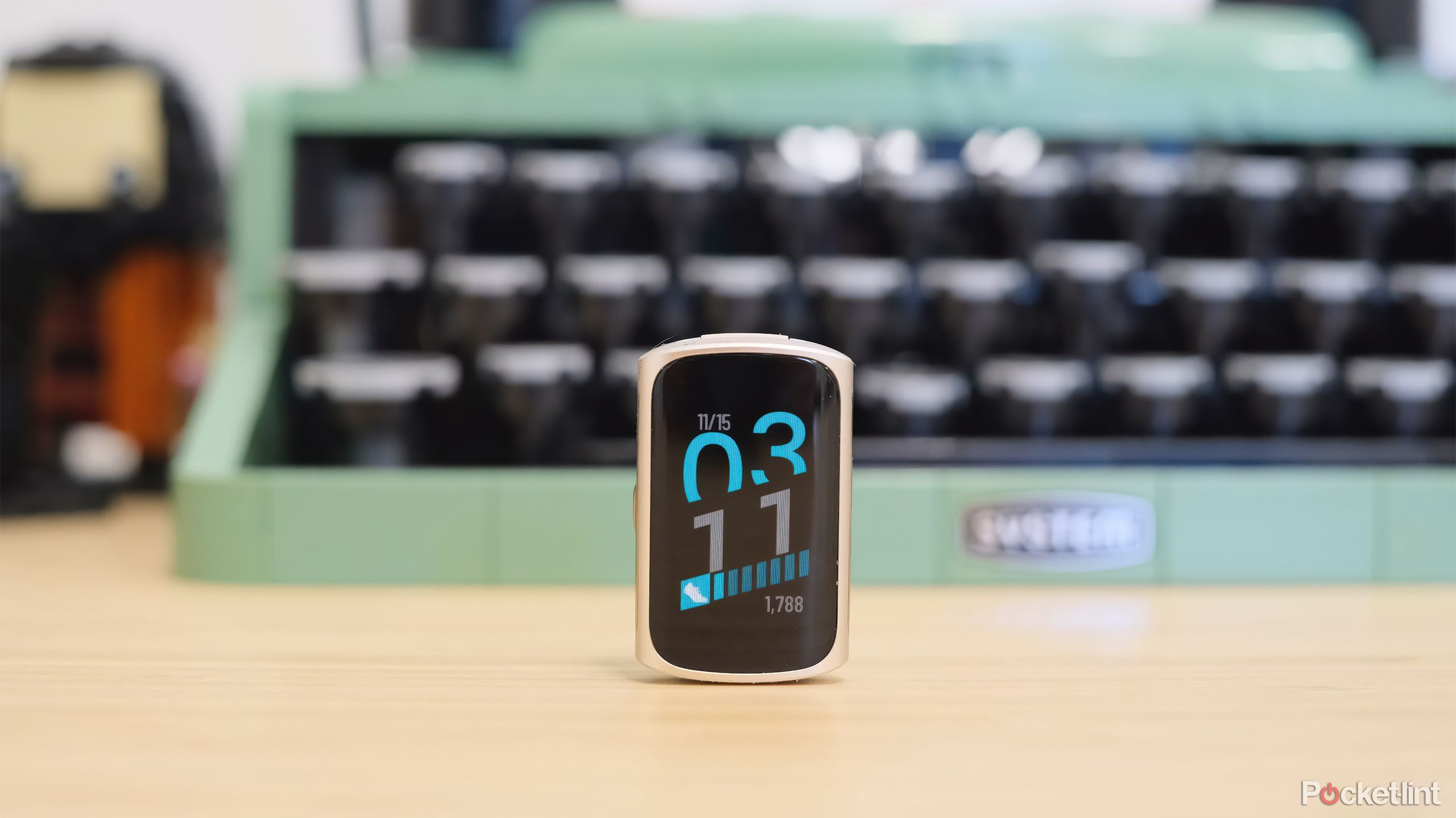 The Fitbit Charge 6 on a desk in front of a mint green typewriter. 