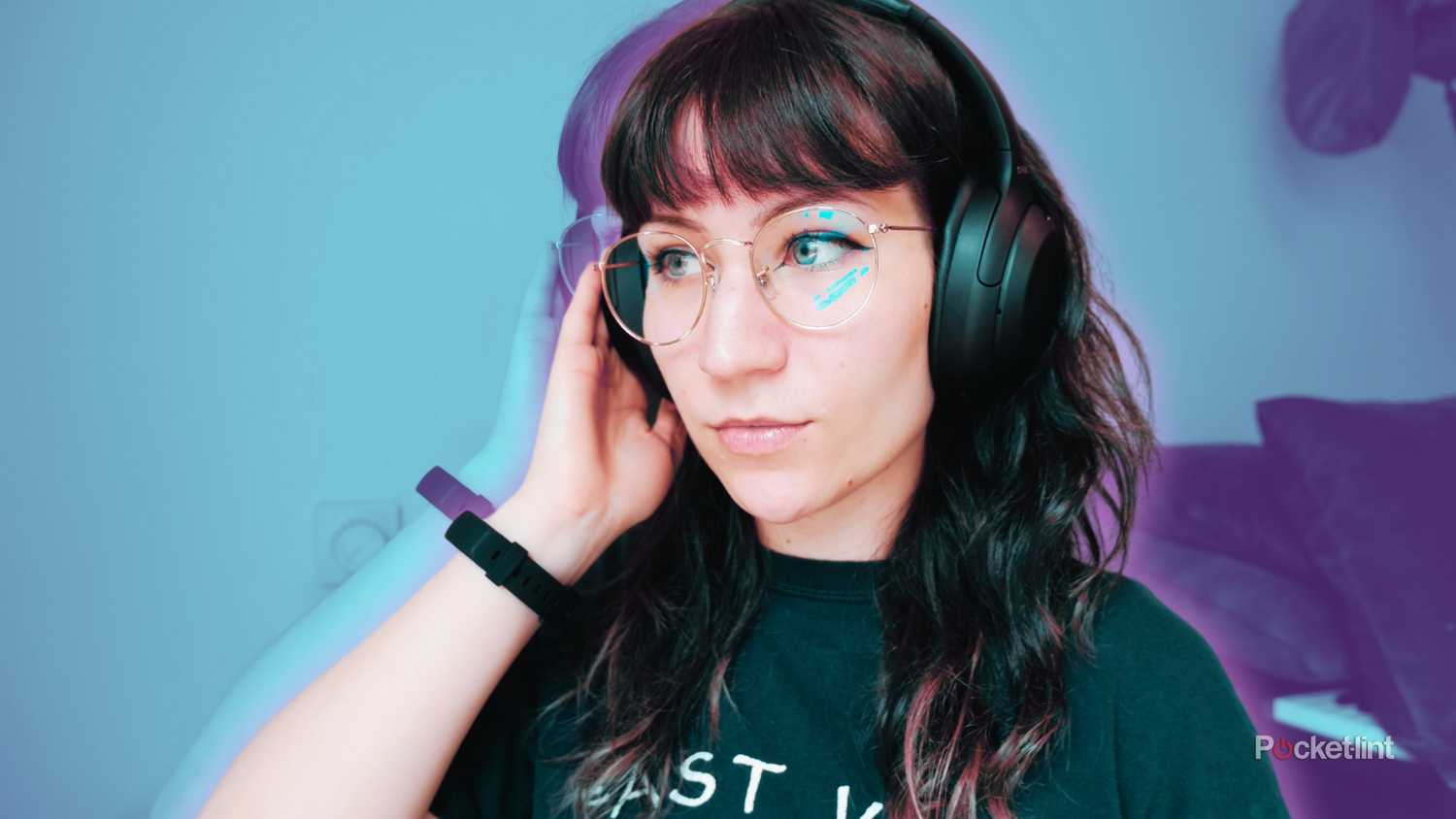 A woman wearing the Sony WH-1000XM4 with a hand cupped over the right side, demonstrating how transparency mode is activated.