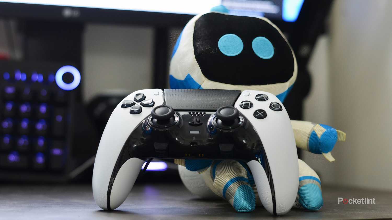 A PlayStation DualSense controller next to an Astrobot plushie.