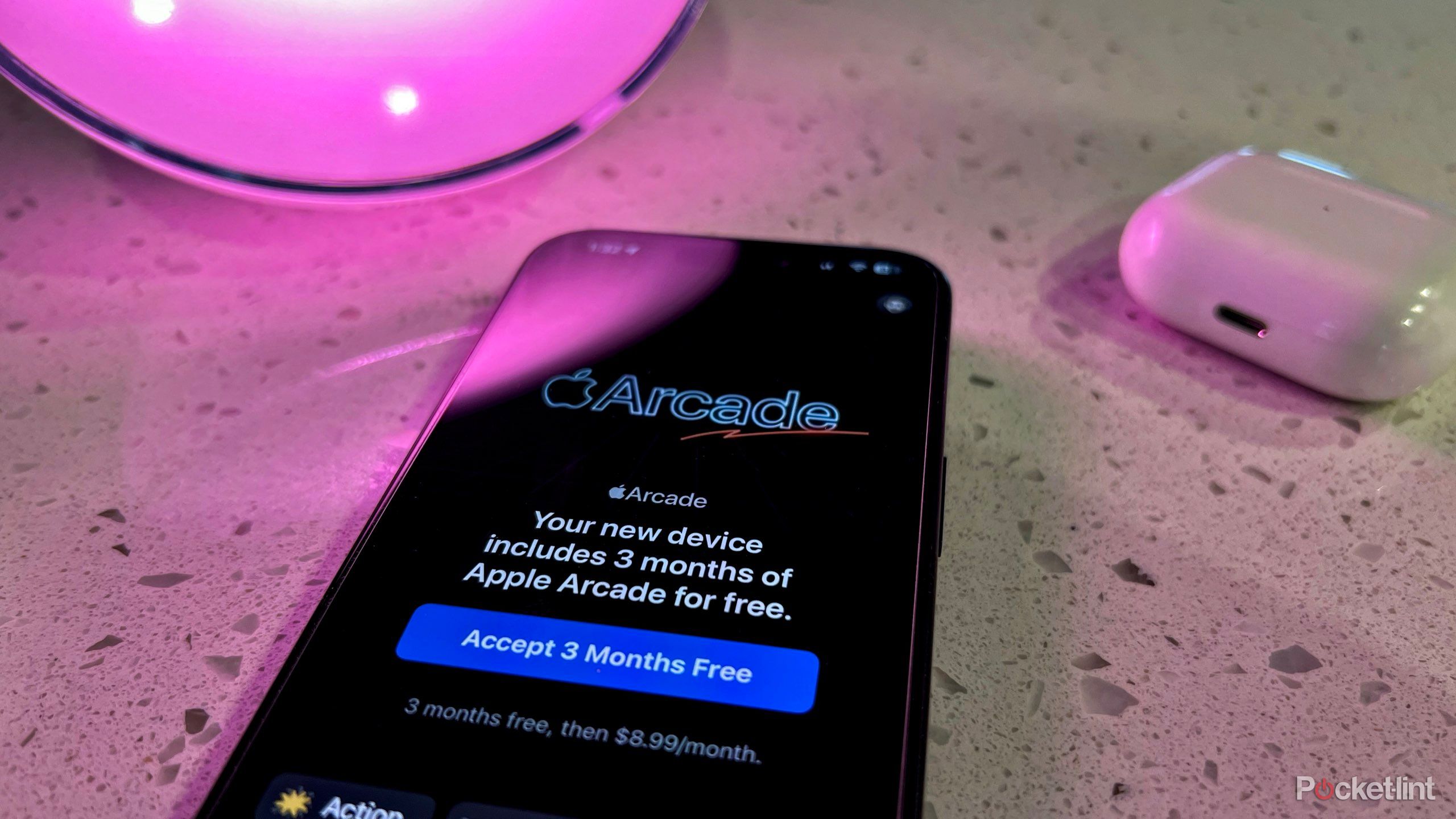 A photo of an iPhone on the Apple Arcade free trial screen with a pink hue.