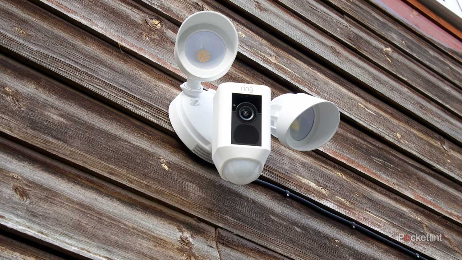 A Ring Floodlight Cam on a wooden wall. 