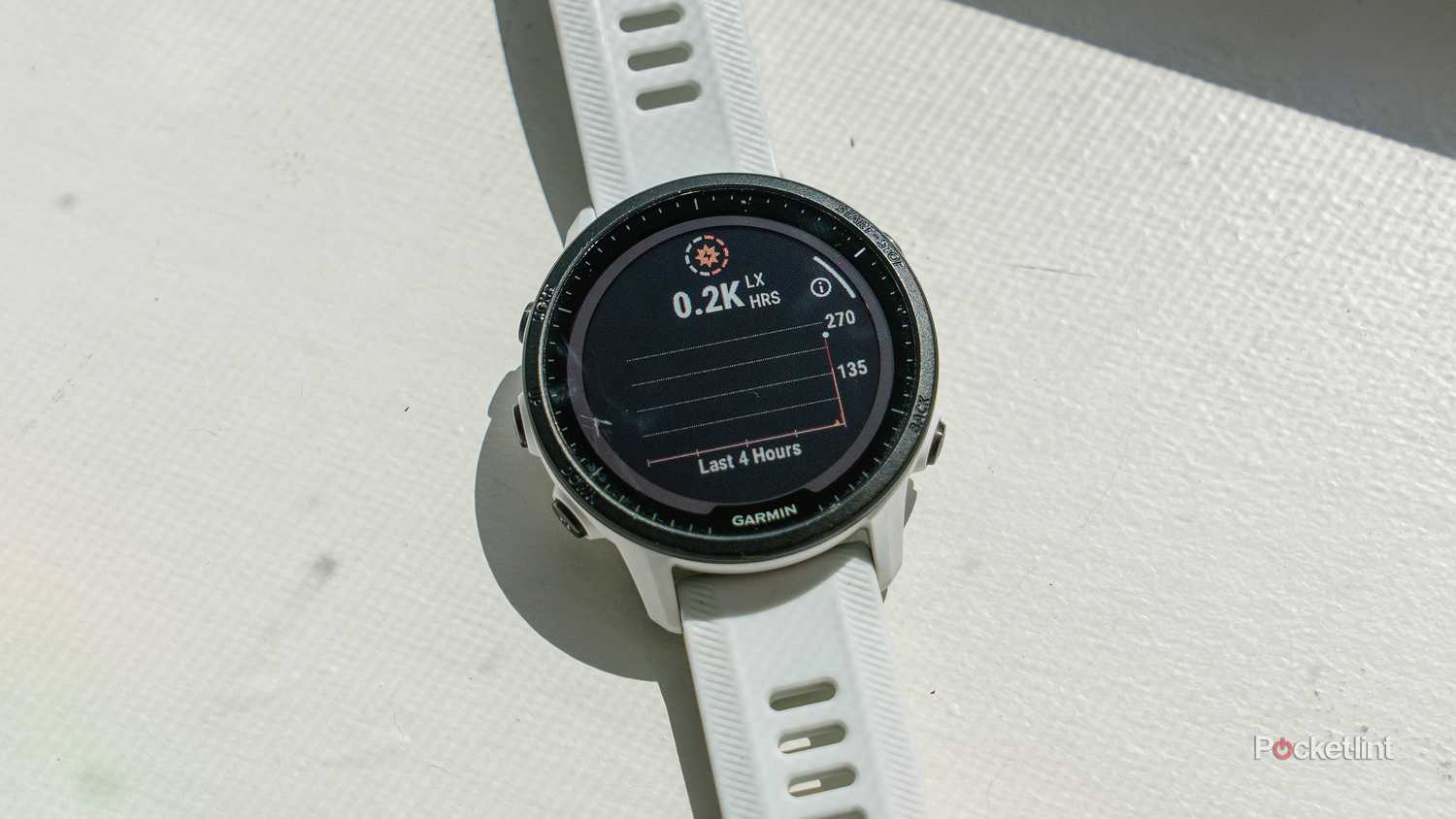 The Garmin Forerunner 955 Solar sits on a white windowsill with the solar intensity menu on the display. 