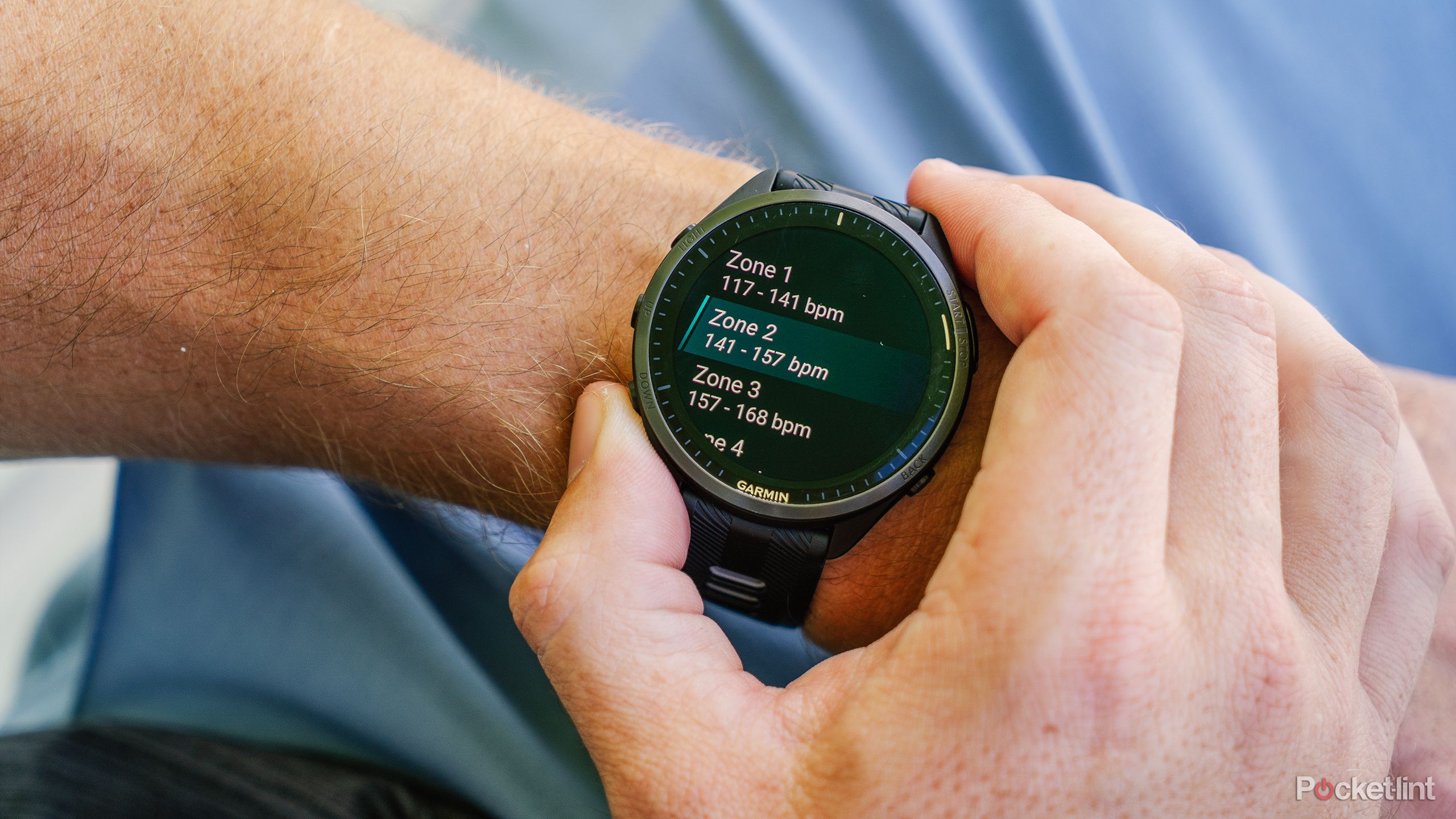 A hand presses buttons on the Garmin Forerunner 965 while it's on a wrist. 