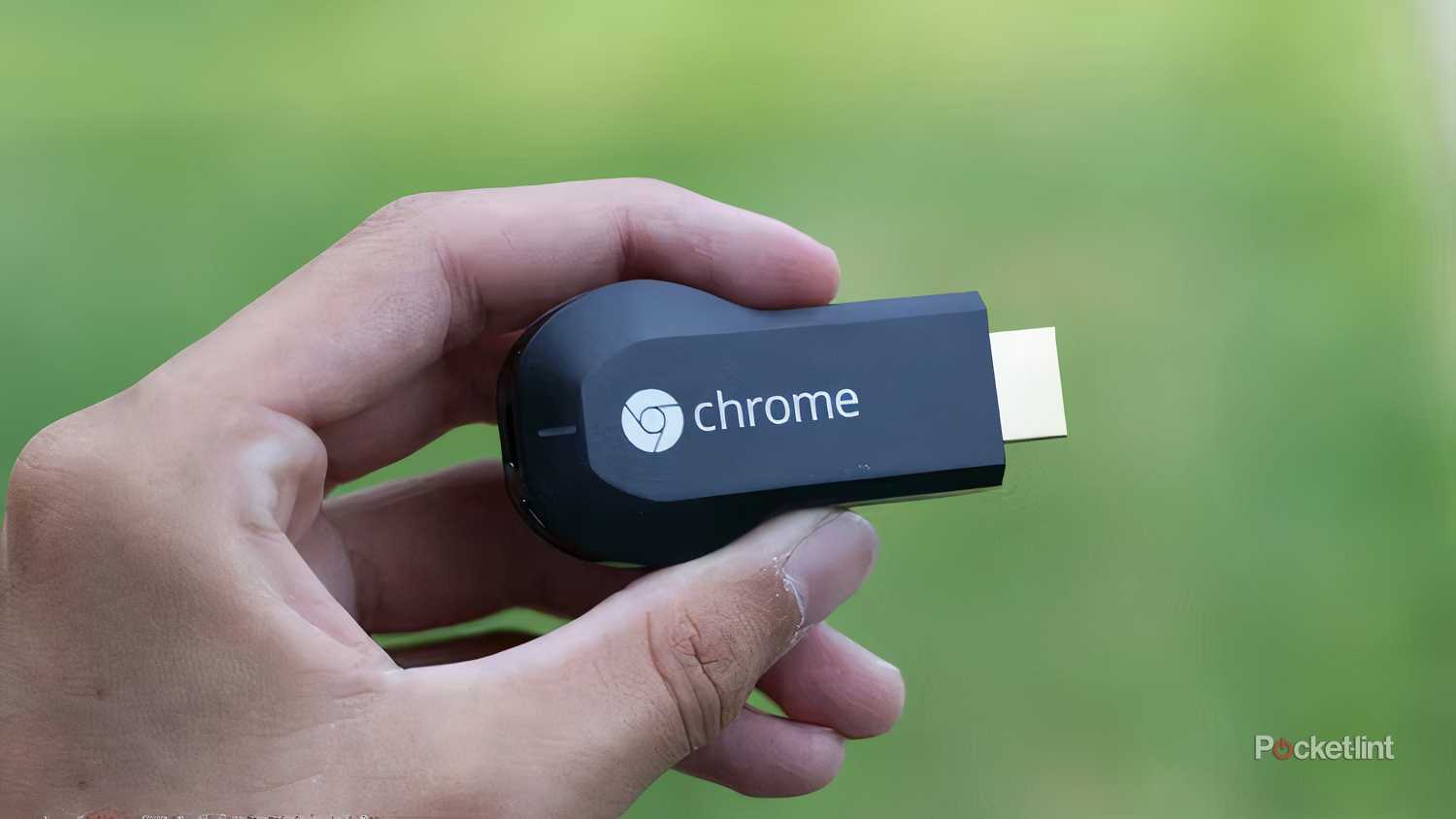 Holding a first generation, dongle-shaped Chromecast.